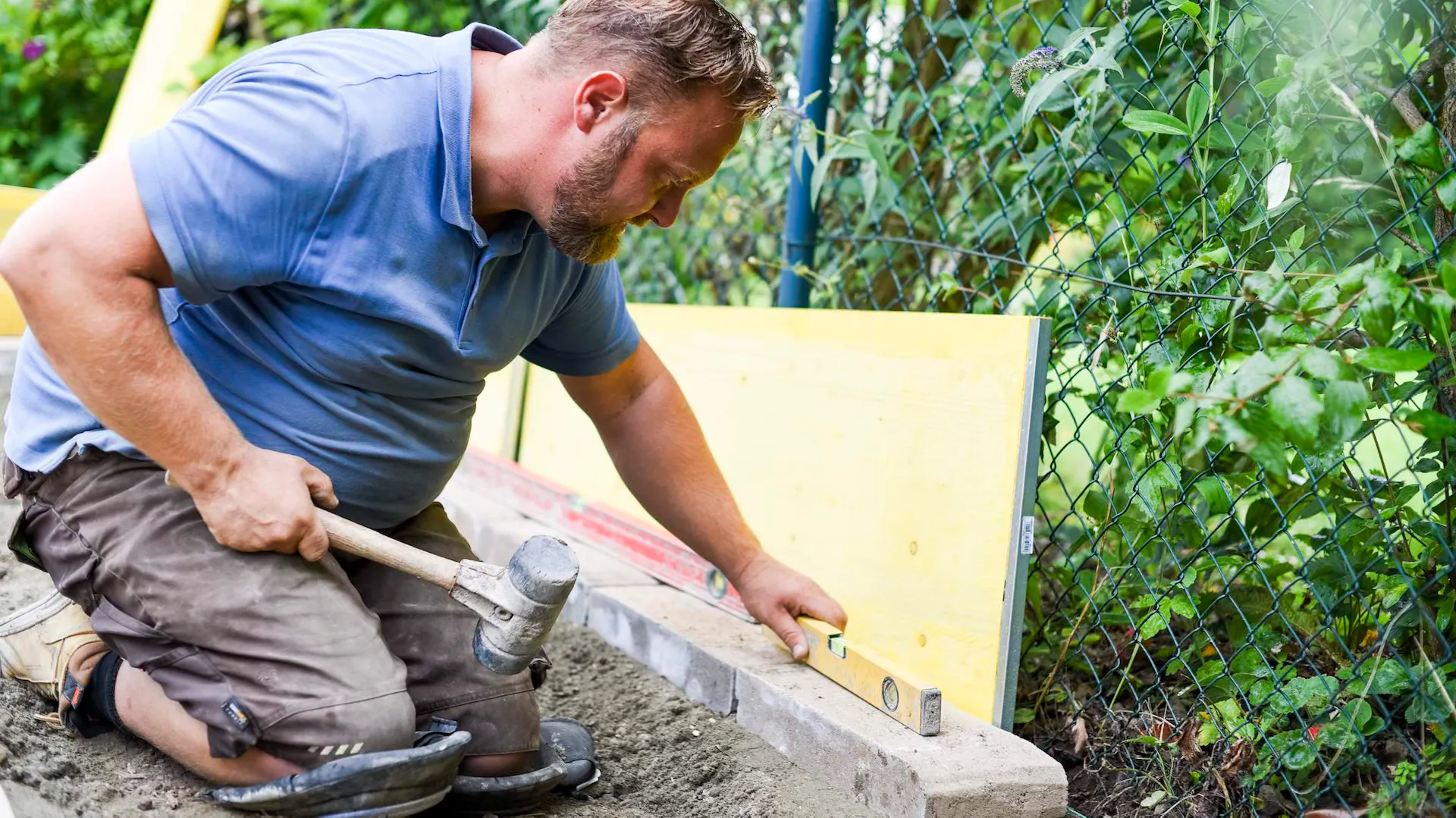 Mann verlegt Trockenmauerstein auf Fundament