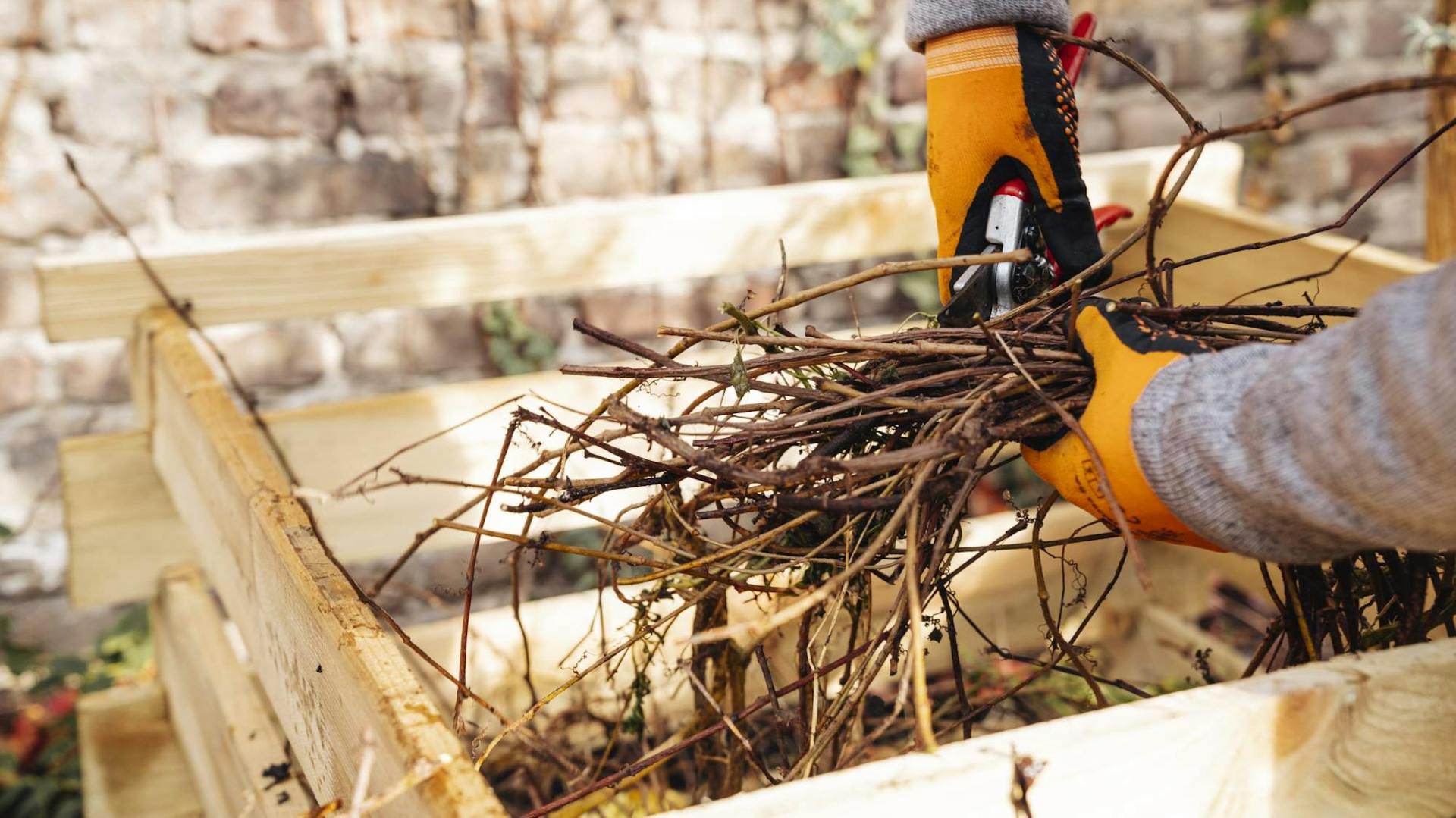 Mann schneidet Äste über neuem Kompost zum Umsetzen