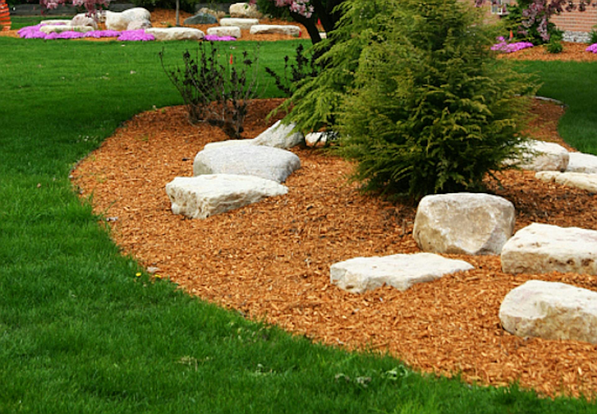 Le pietre bianche poggiano su una superficie rivestita con pacciame decorativo e piantata a cespugli