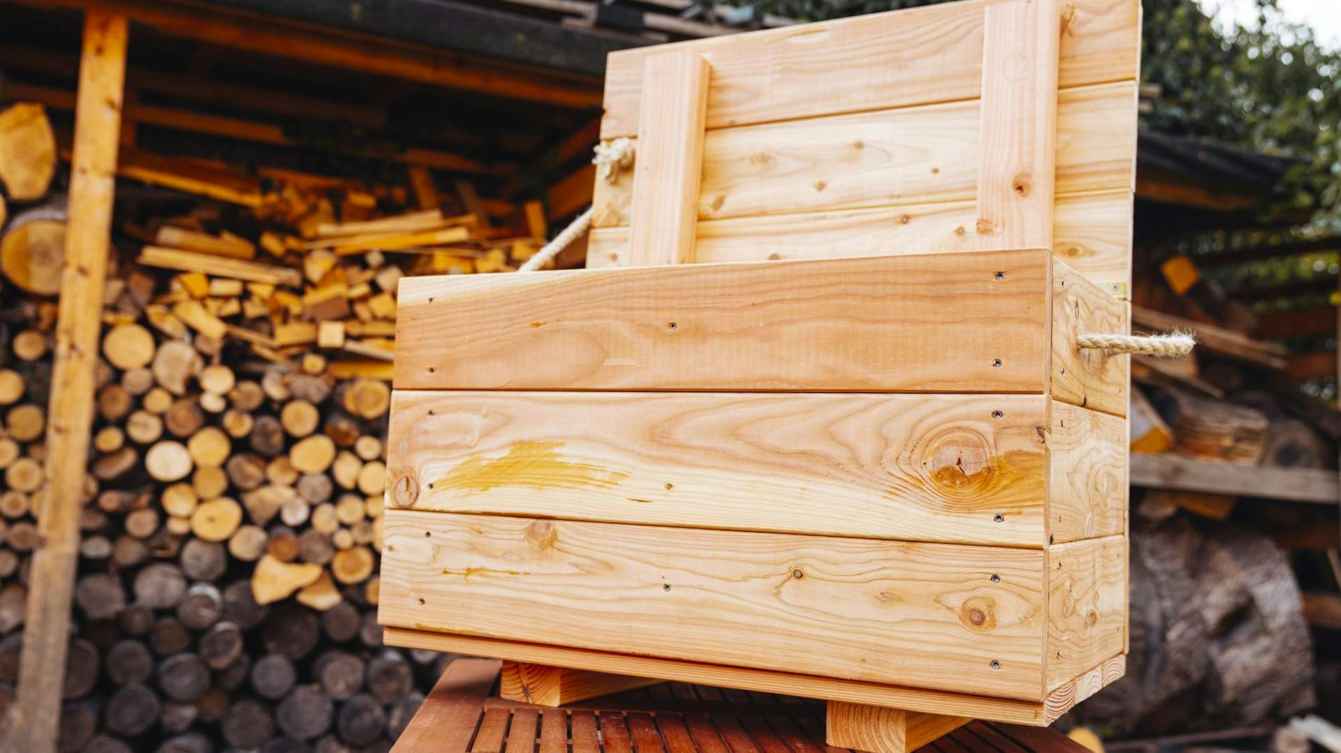 Fertige selbstgebaute Wurmkiste vor gelagertem Feuerholz