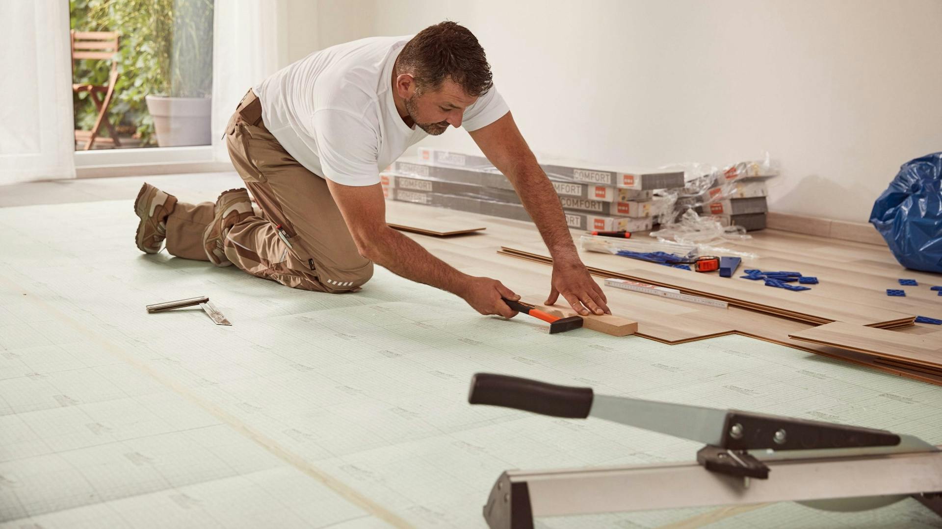 Heimwerker verlegt Laminat mit Hammer und Schlagklotz
