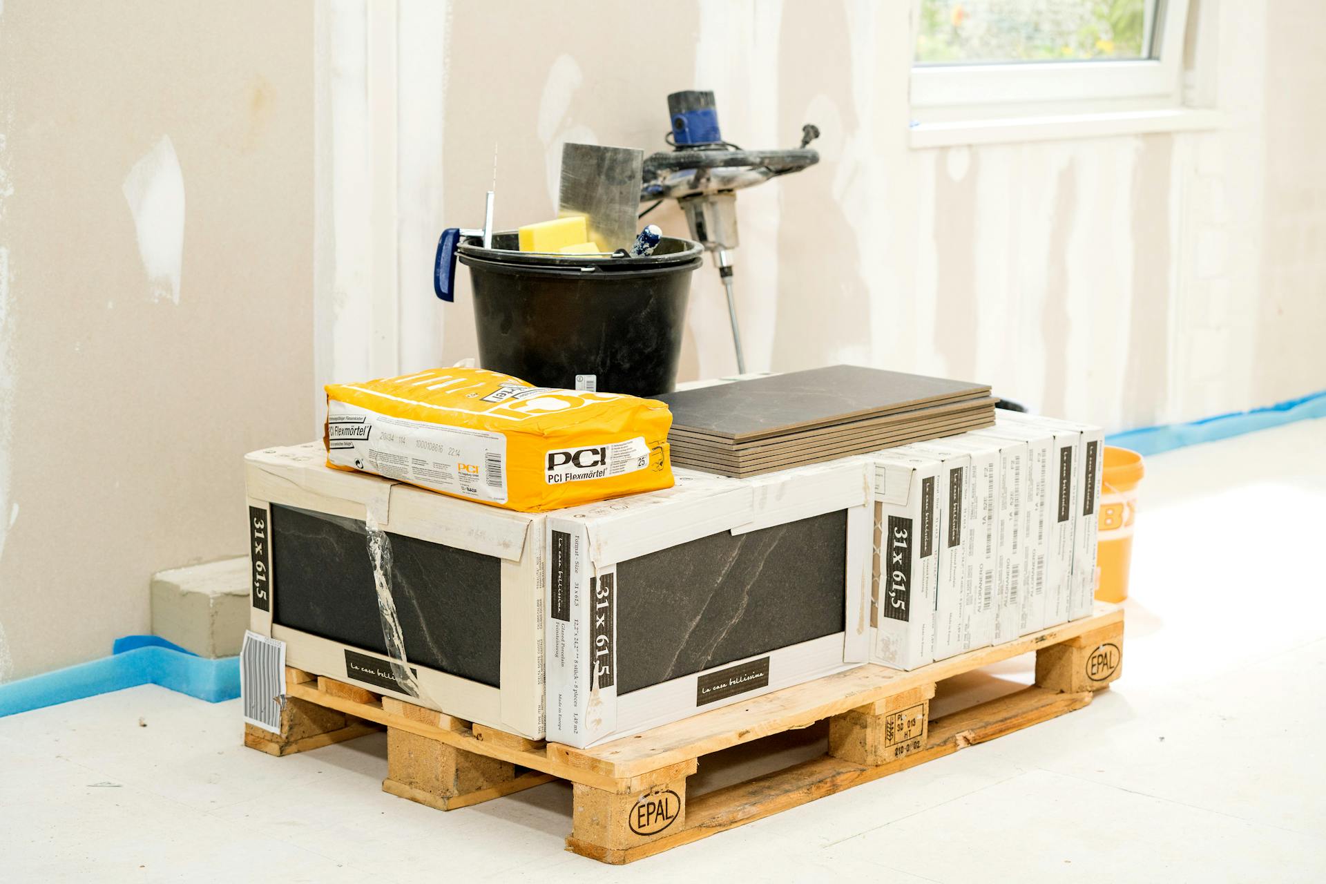 Il materiale necessario come piastrelle e colla posizionato su un pallet.