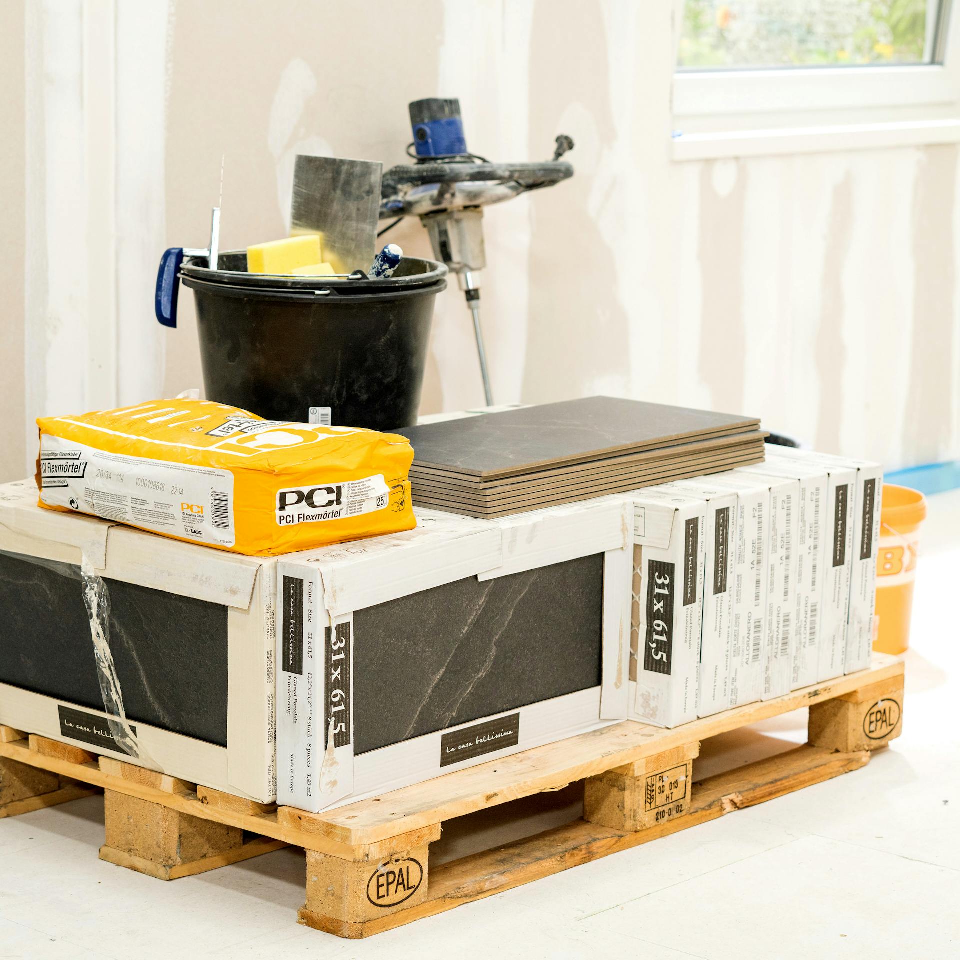Der Materialbedarf wie Fliesen und Fliesenkleber steht auf einer Palette bereit.