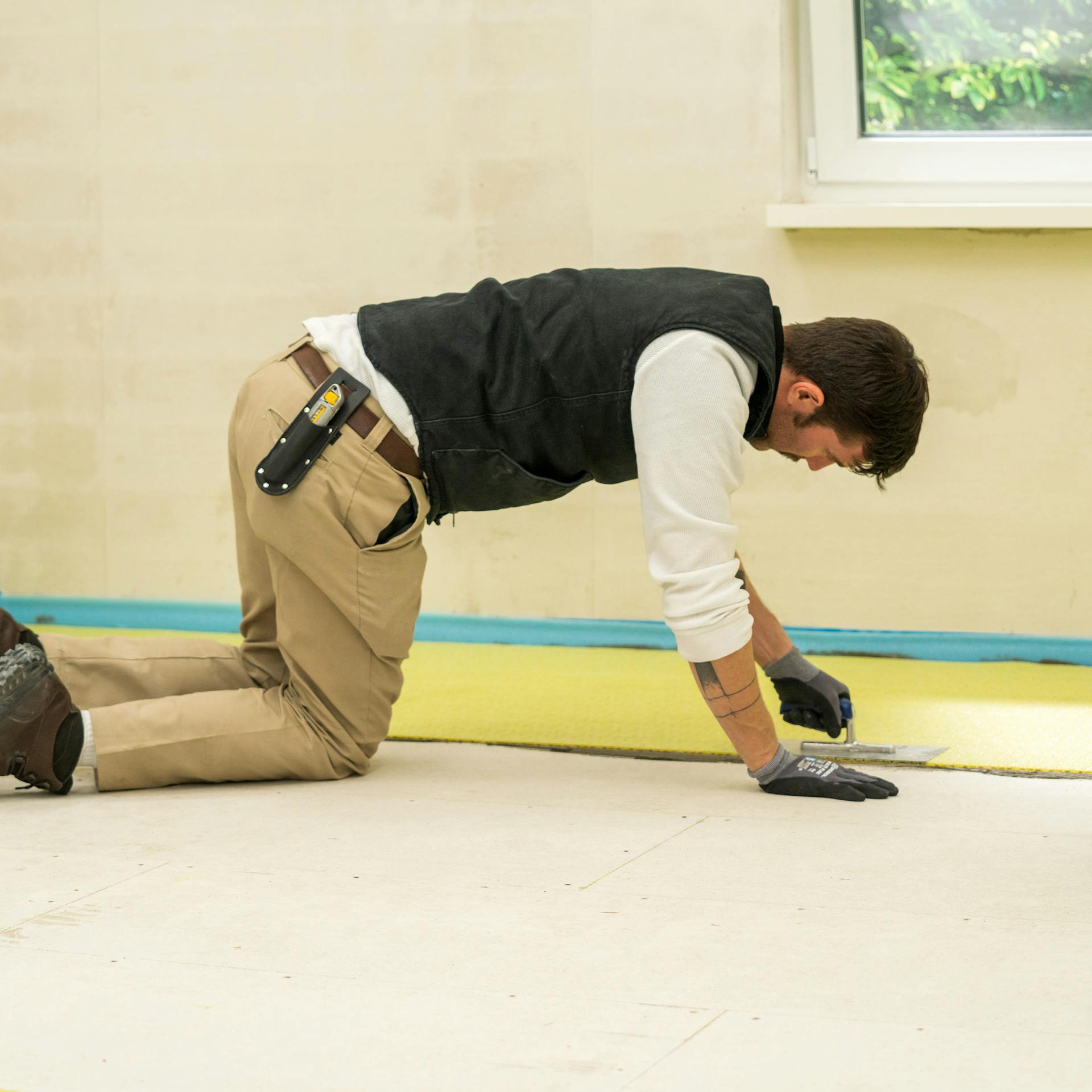 Heimwerker verlegt eine Entkopplungsmatte.