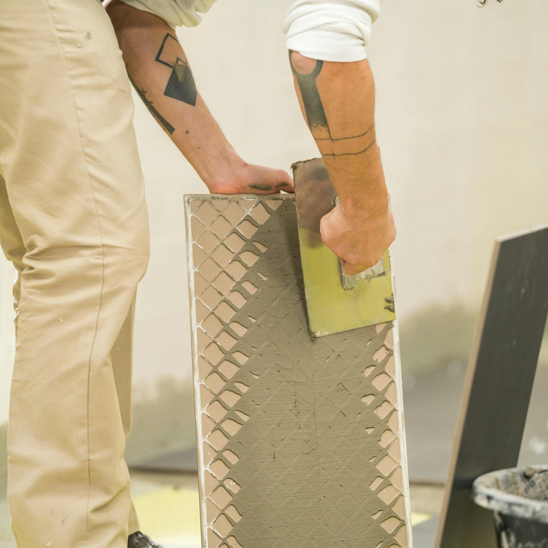 Heimwerker trägt Fliesenkleber auf den Fliesenrücken auf.