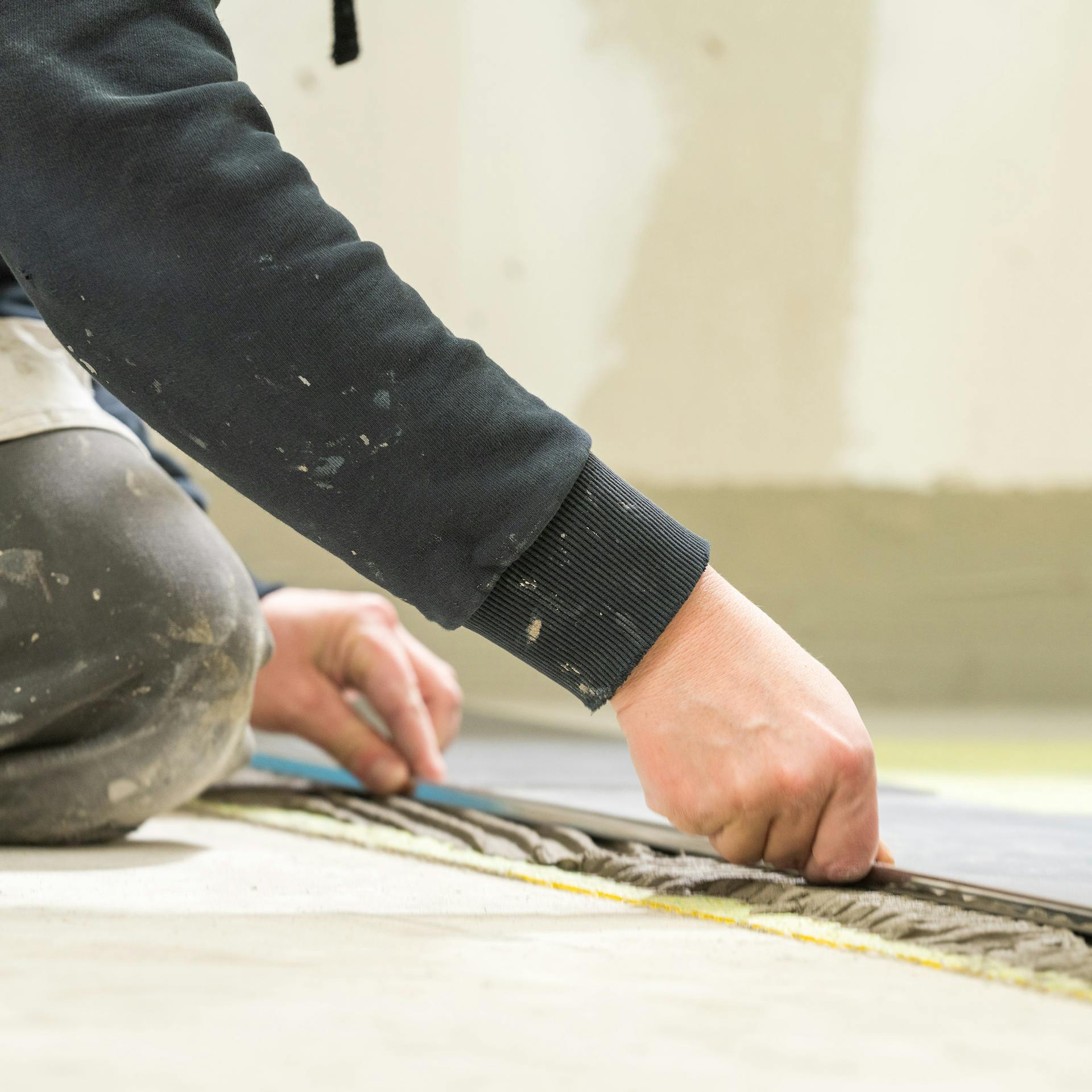 Heimwerker setzt Randfliesen auf den Fliesenkleber.