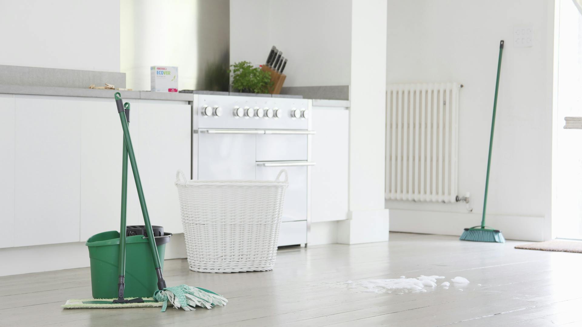 Putzeimer und Bodenwischer auf Boden in Raum