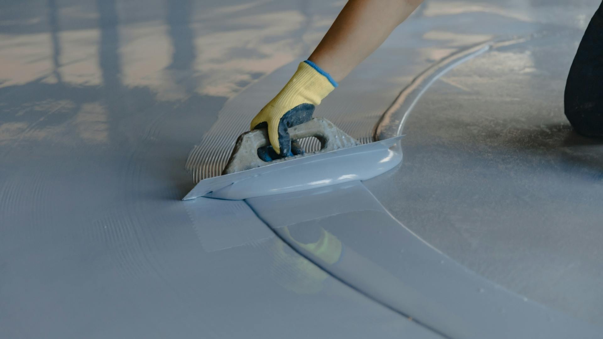 Eine Person versiegelt einen Garagenboden.