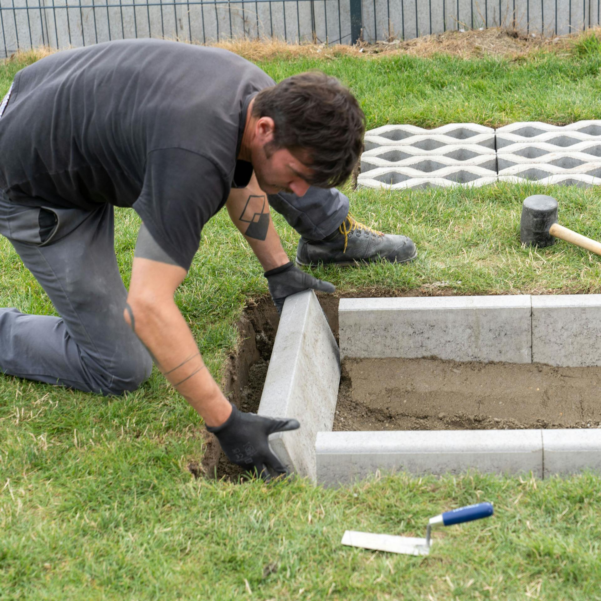 Muž ukladá obrubník do jamy