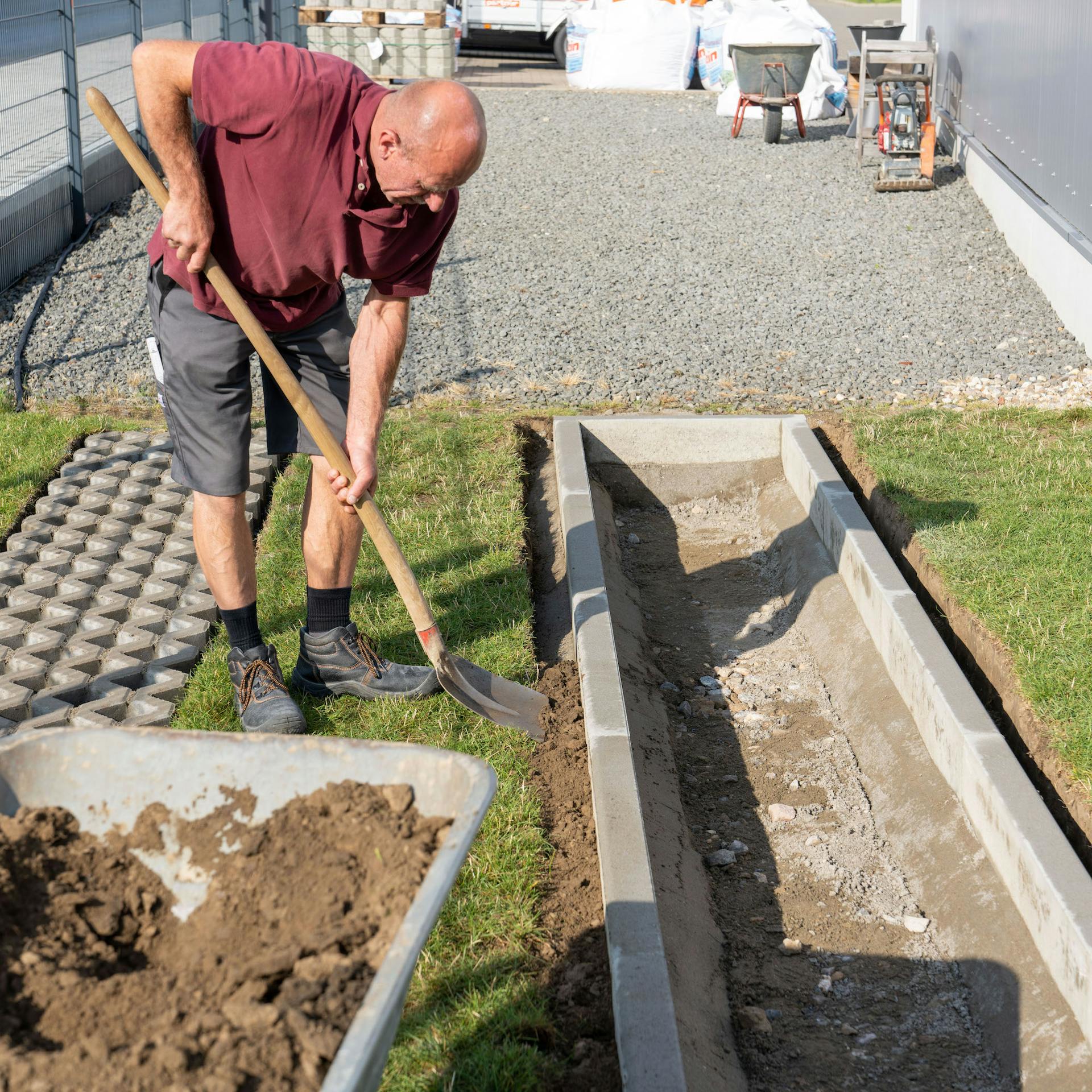 Osoba dáva lopatou zeminu za obrubníky