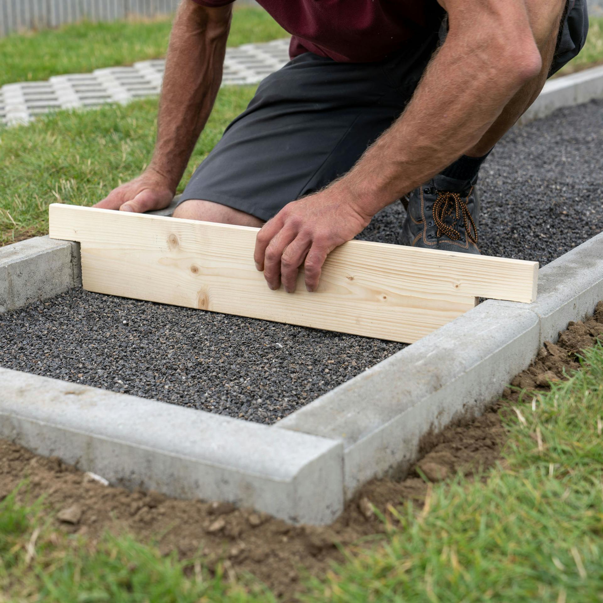 Muž zarovnáva zrezanou doskou vrstvu drviny