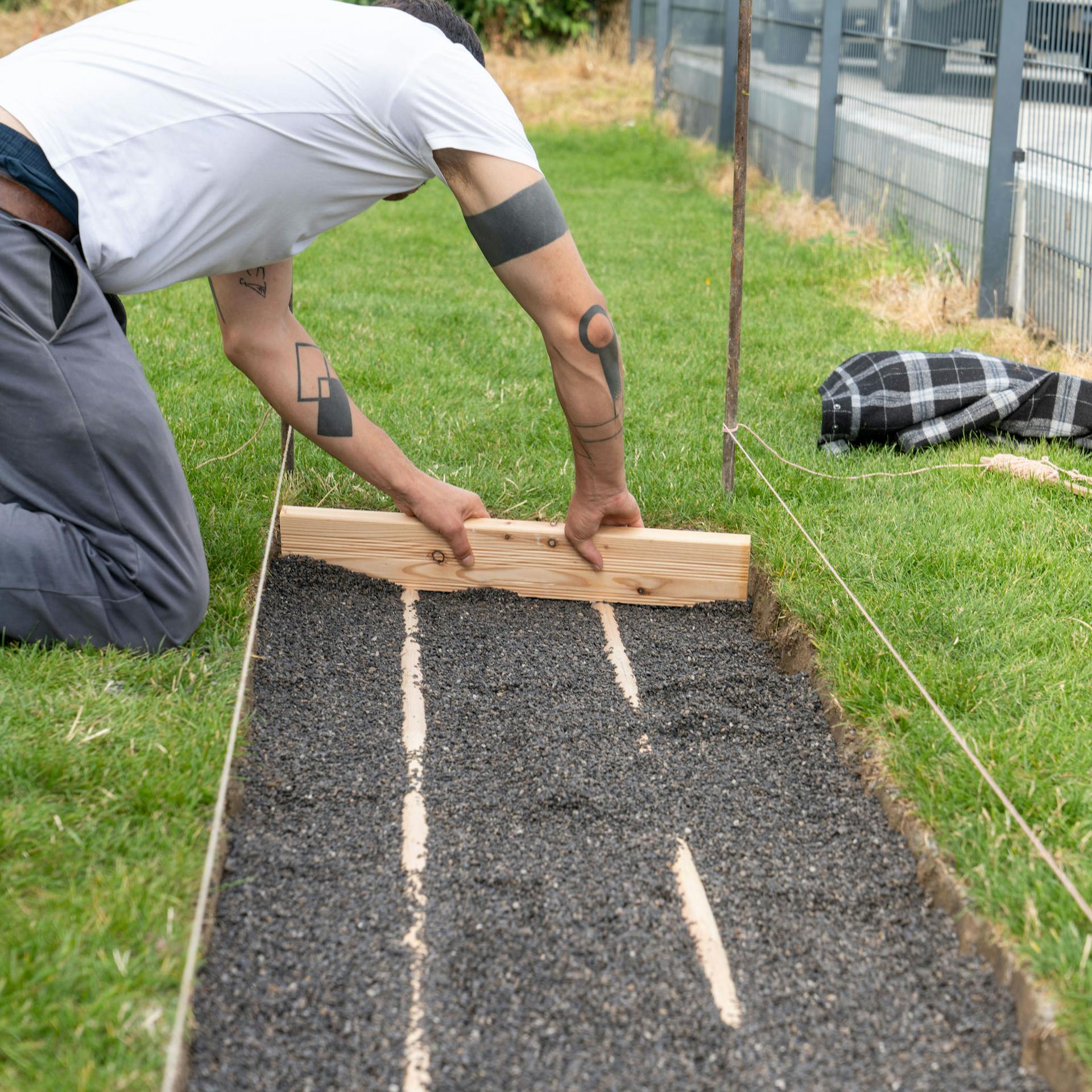 Muž vyhladzuje drevenou doskou vrstvu drviny