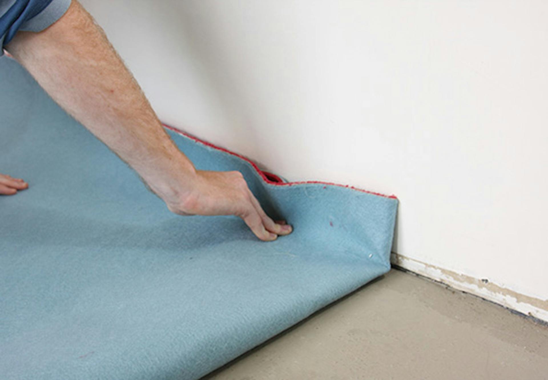 Pracovník rozkladá koberec v miestnosti.