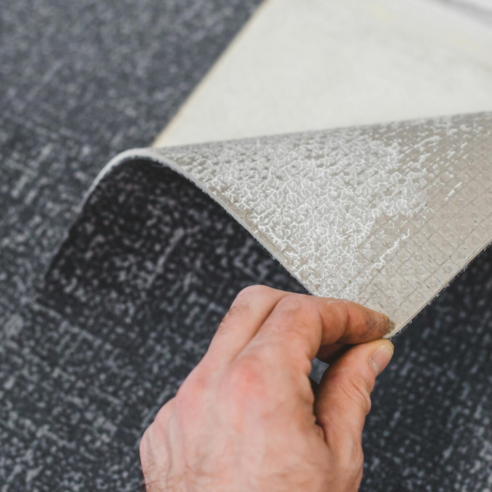 Egy ember felemeli a padlószőnyeg sarkát