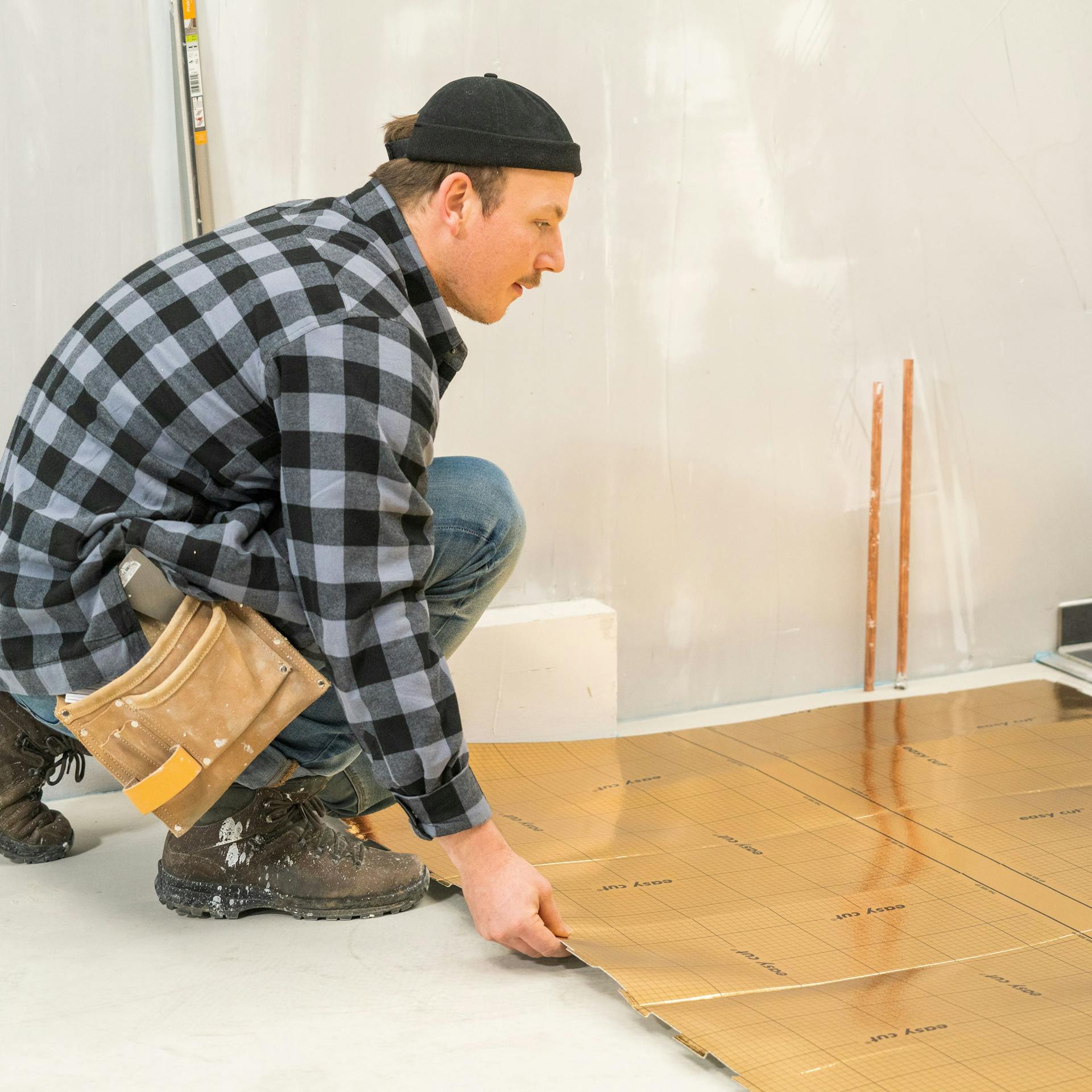 Handwerker verlegt die Trittschalldämmung unter dem Vinyl.