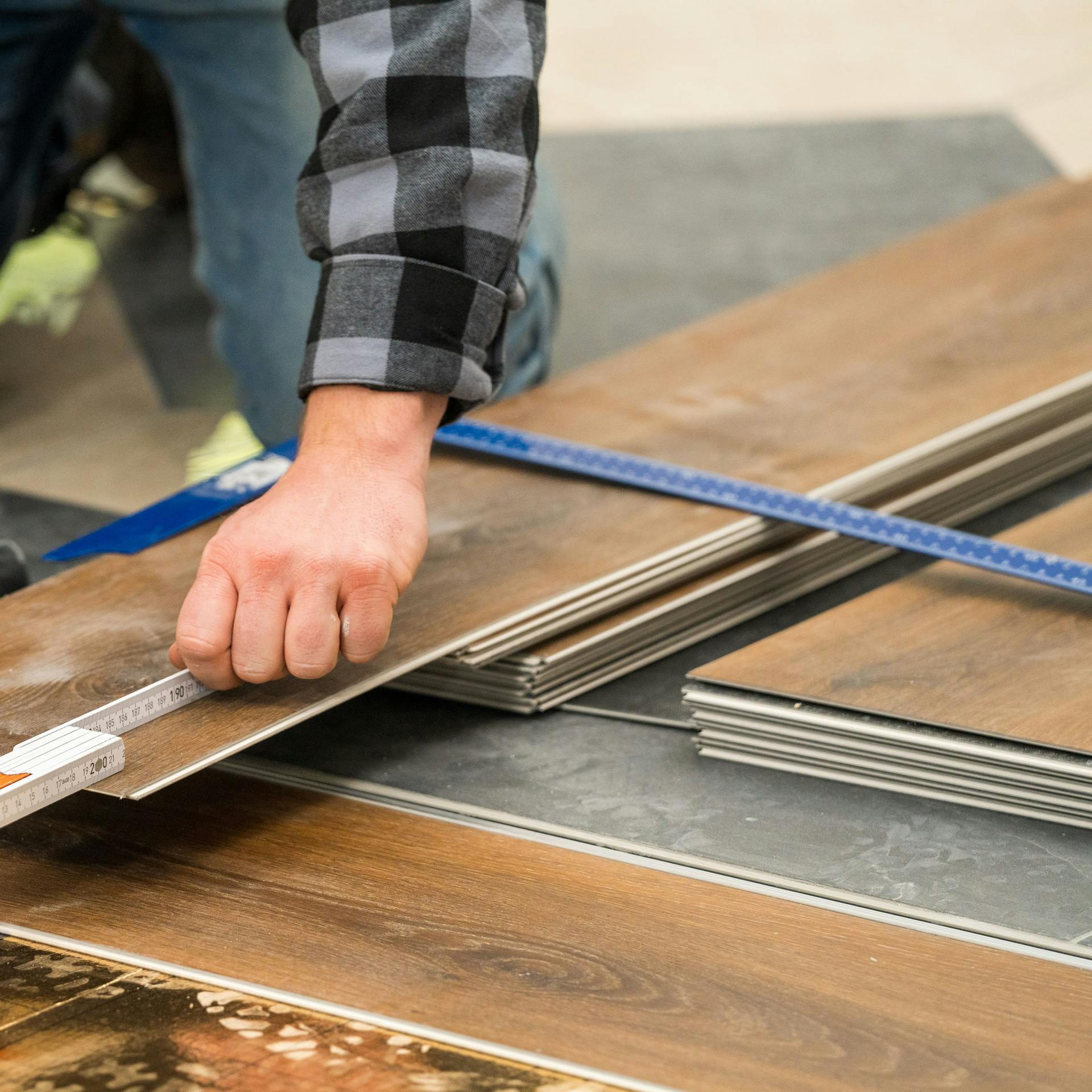 Handwerker misst die Diele mit einem Zollstock aus.