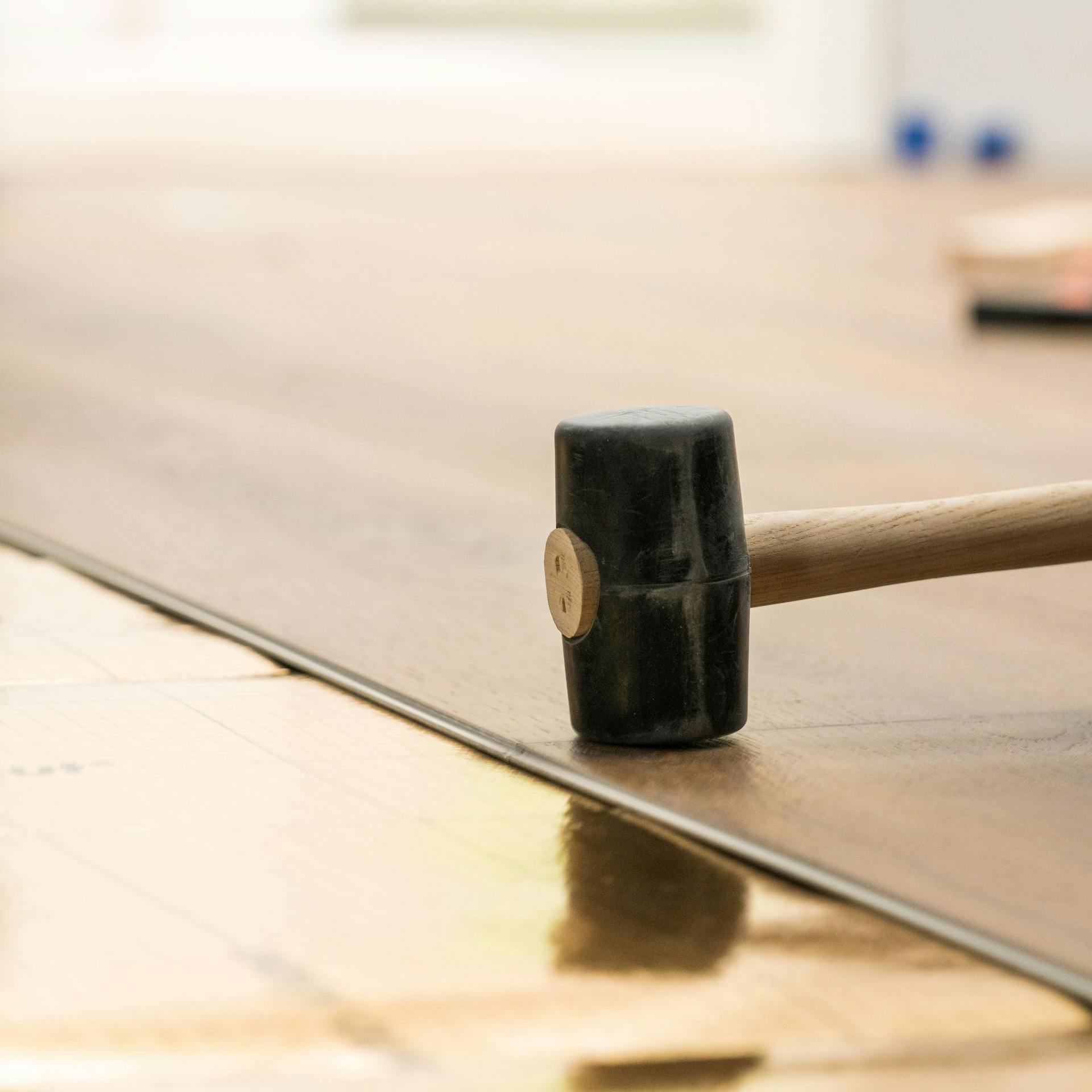 Heimwerker klopft das Vinyl mit einem Hammer fest.