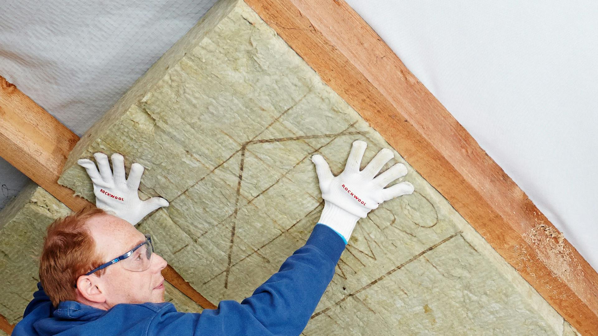 Dach wird mit Dämmmaterial von einem Heimwerker gedämmt.