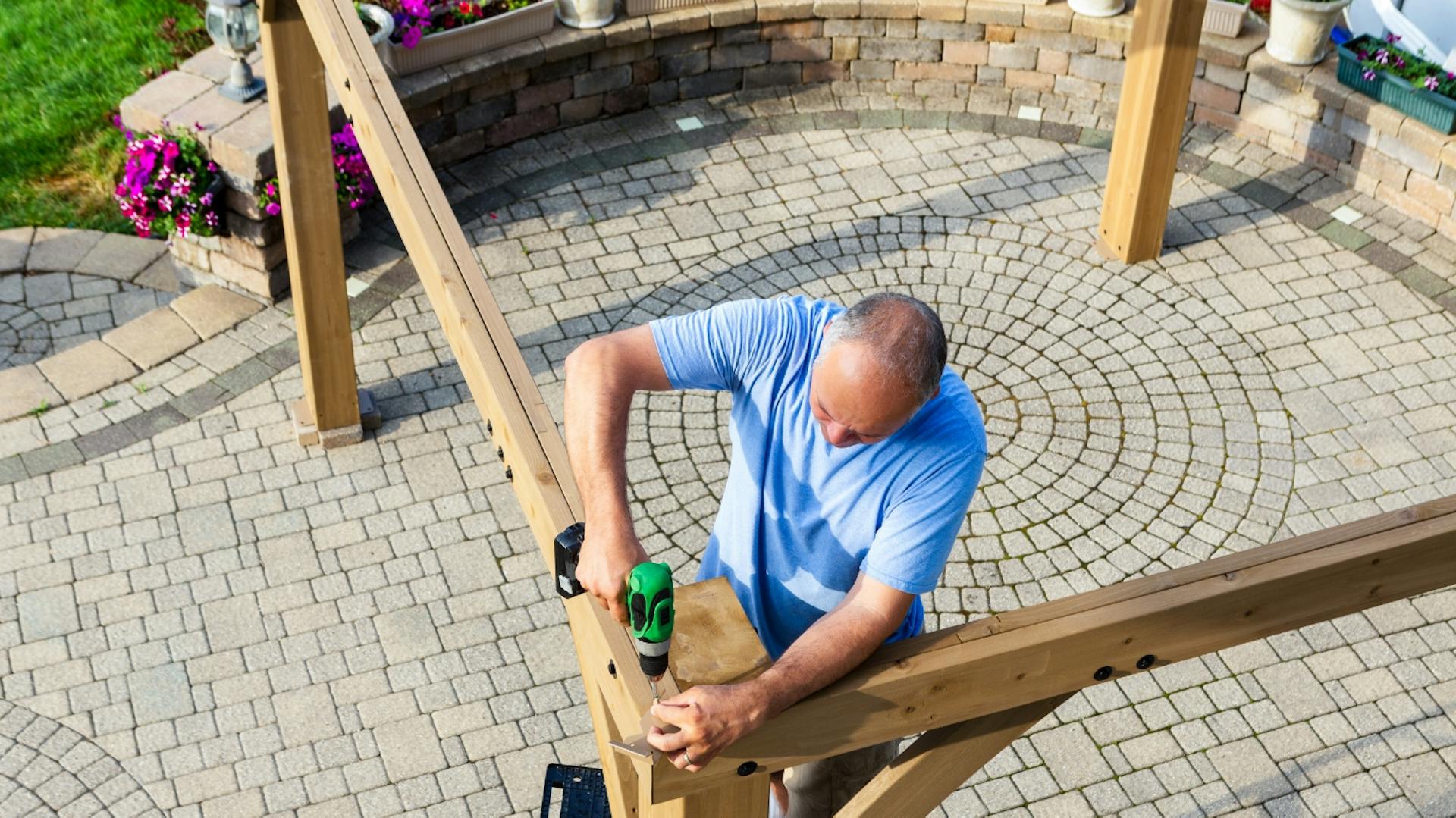 Mann verschraubt Holzlatten miteinander.