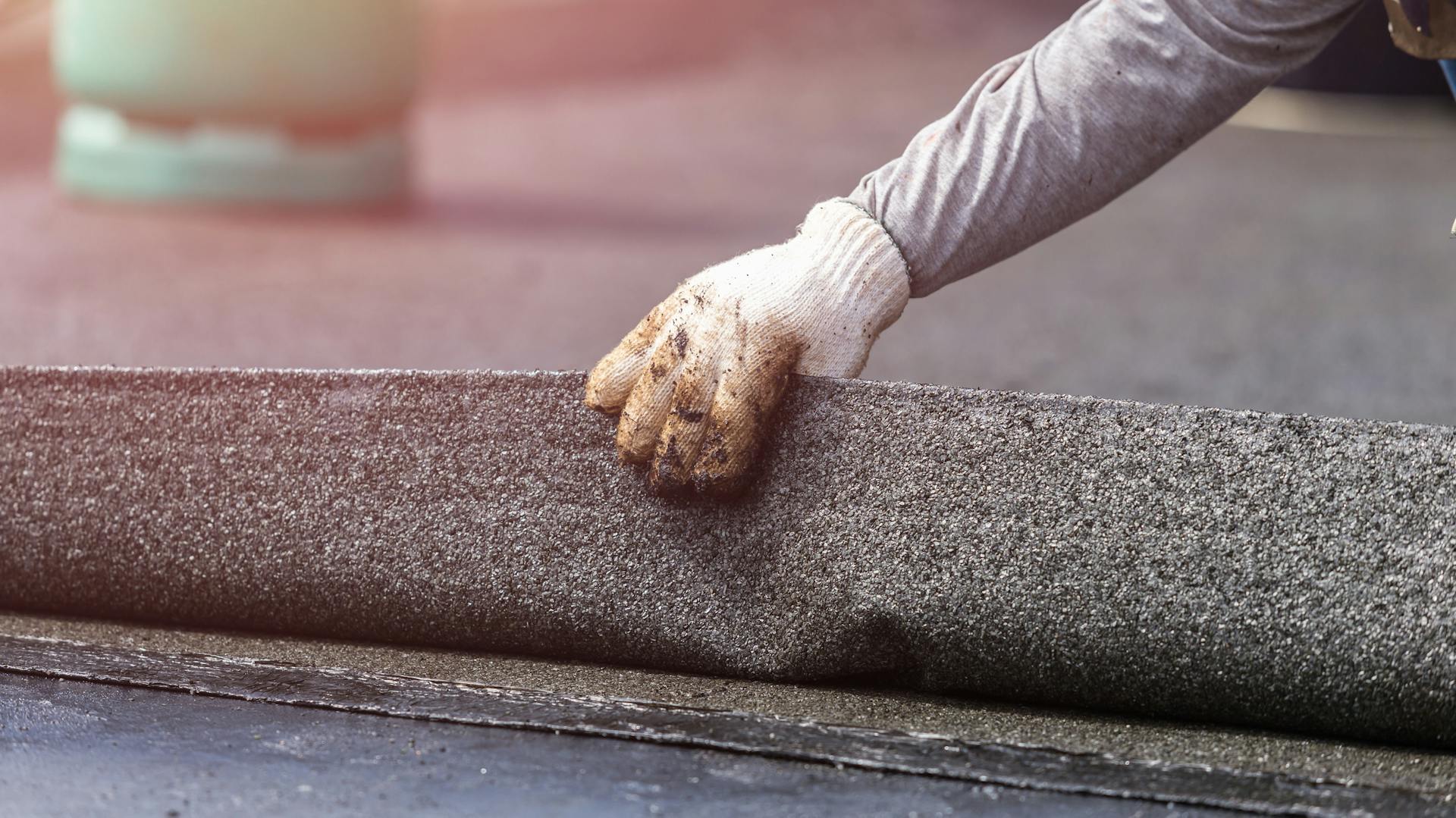 Eine Person entfernt Dachpappe von einem Dach