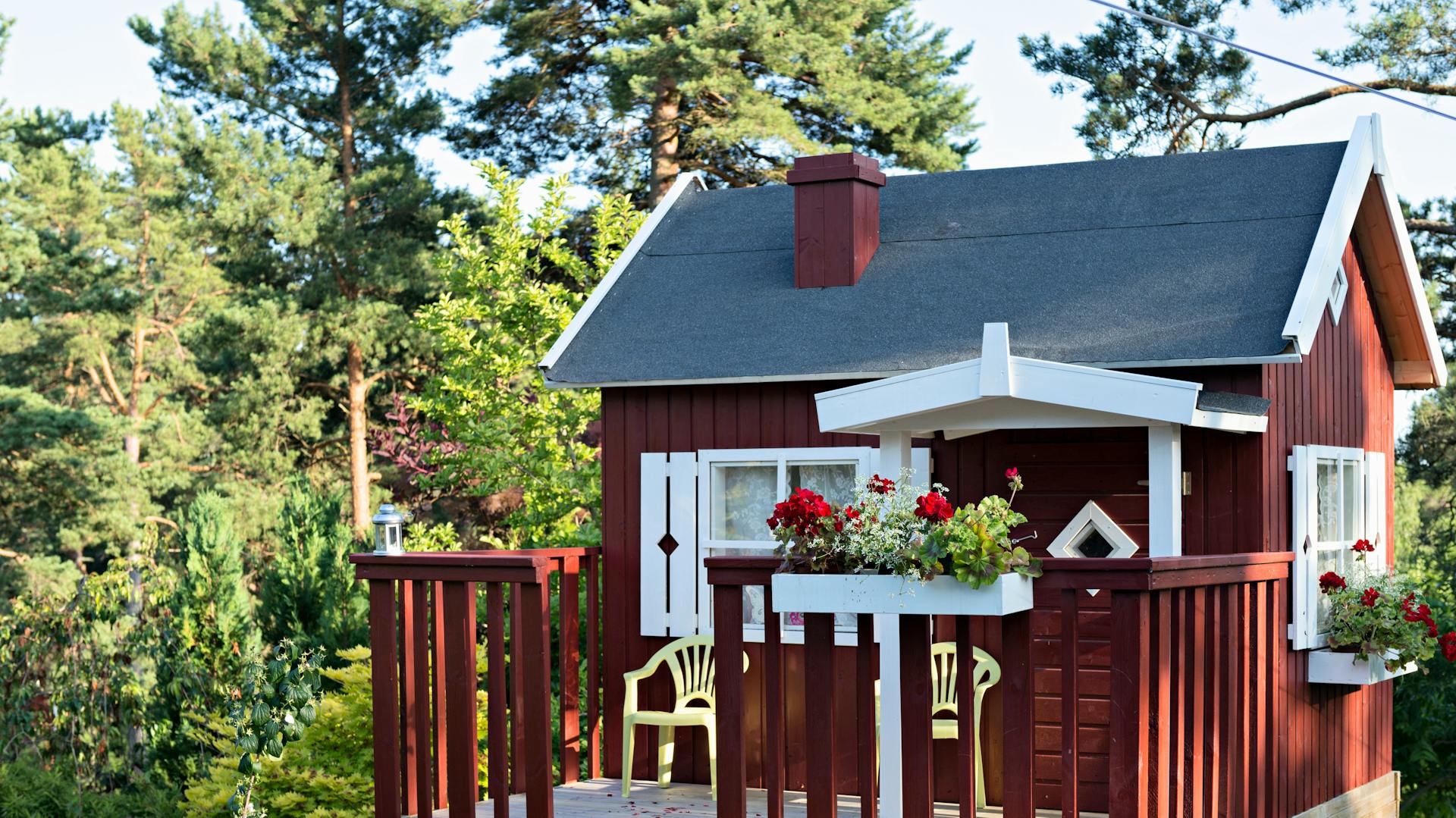 Červený zahradní domek s upevněnou krytinovou lepenkou.