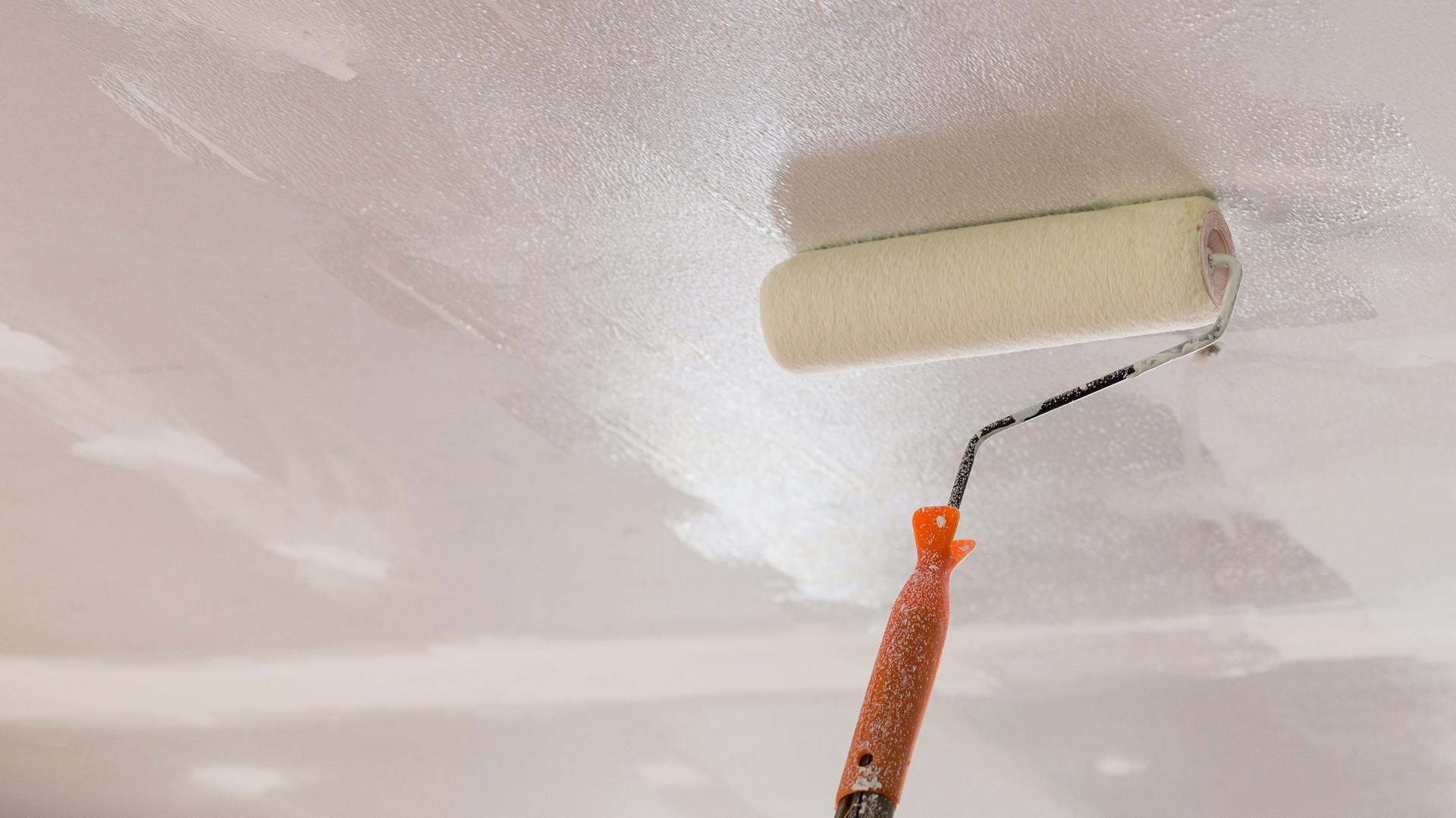 Jemand trägt Tiefengrund auf eine Decke auf.