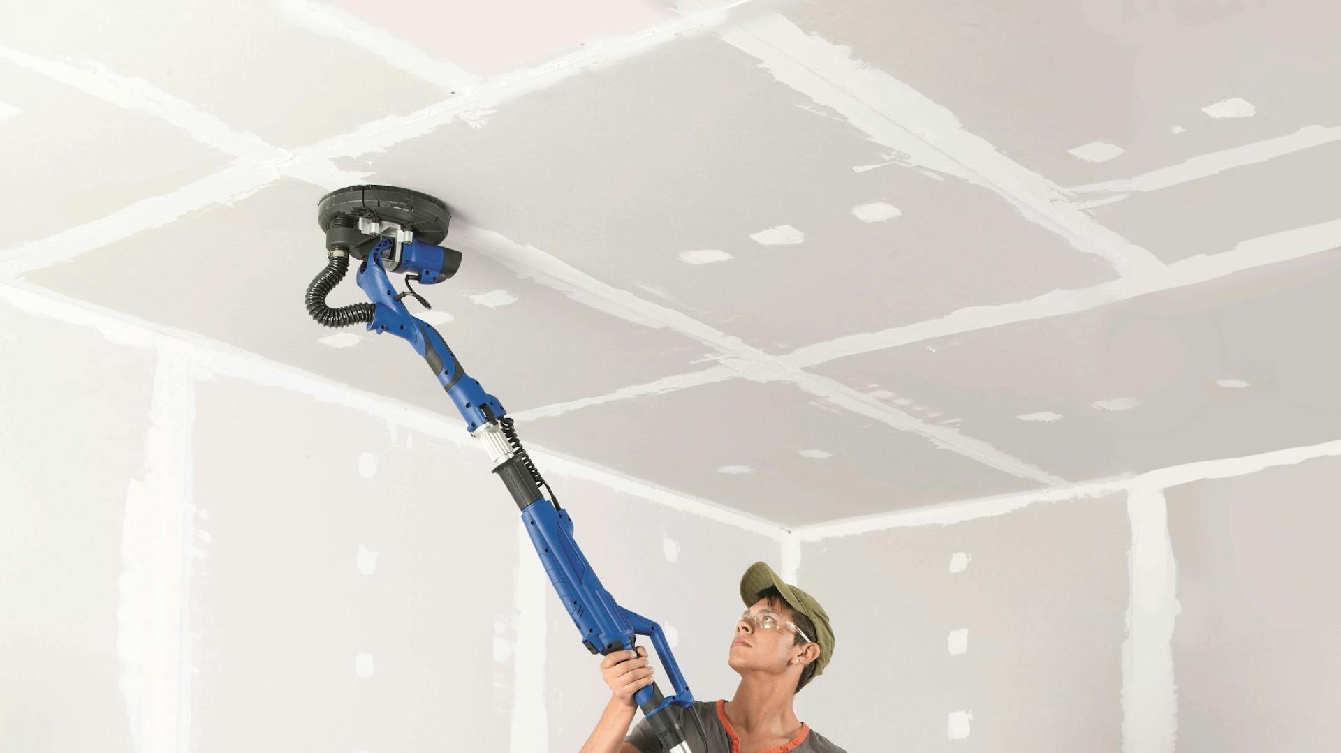 Muž drží nástroj na čistenie stropu.