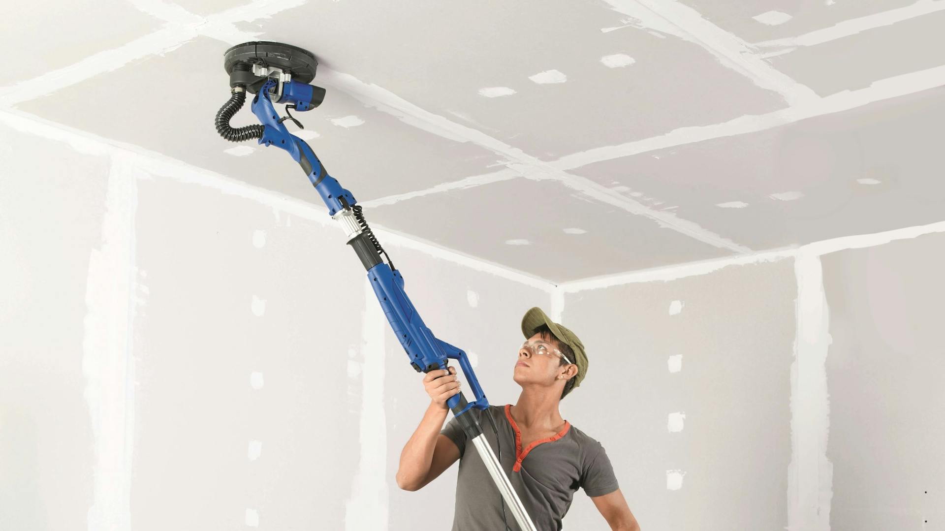 Heimwerker bearbeitet Deckenverkleidung mit Trockenbauschleifer