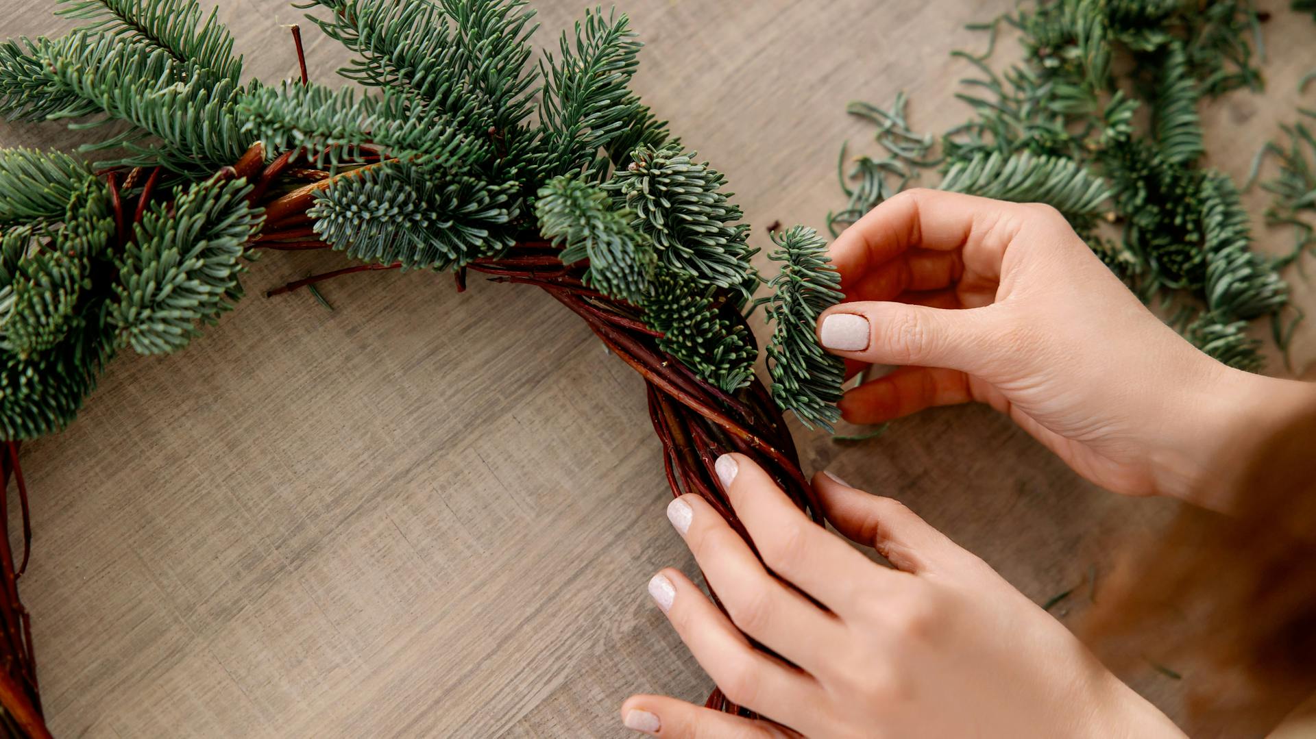 Jemand bindet einen Adventskranz.
