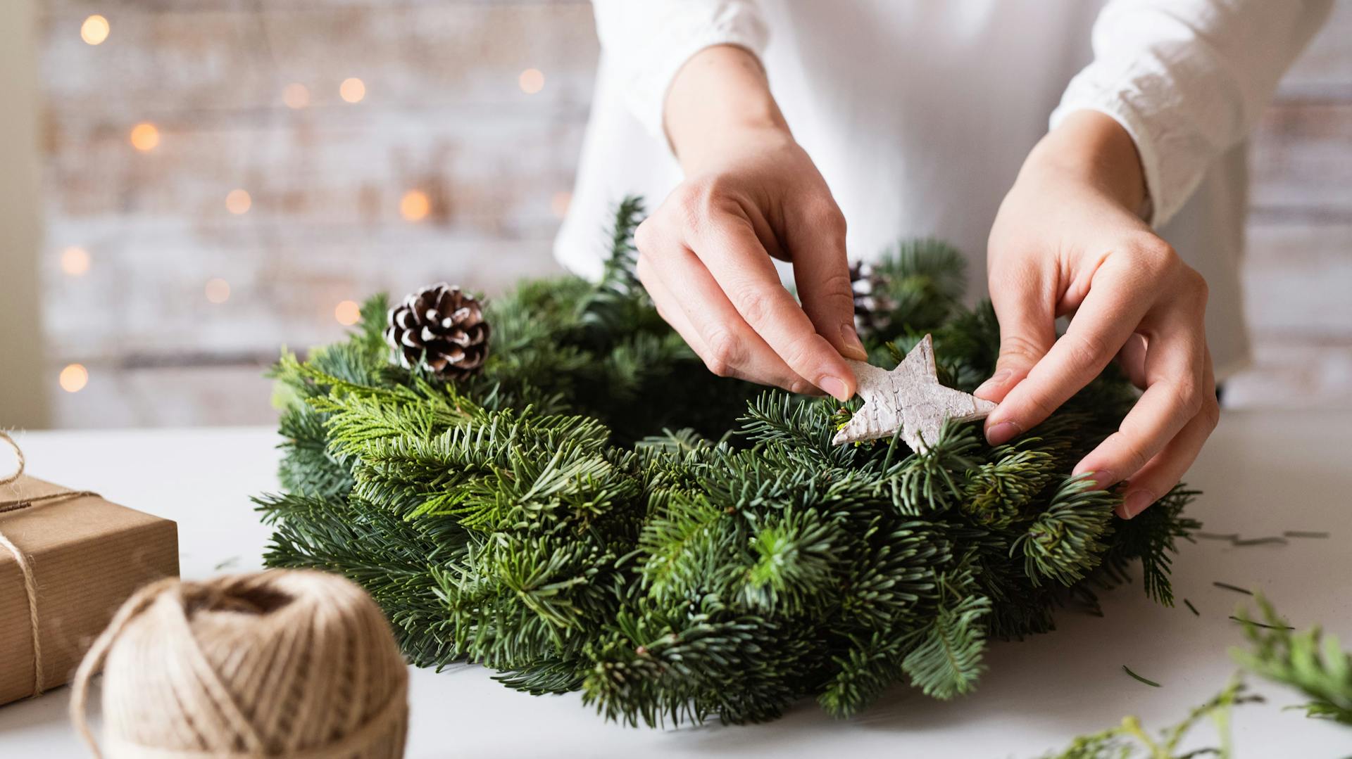 Eine Person bringt Dekoration am Adventskranz an.