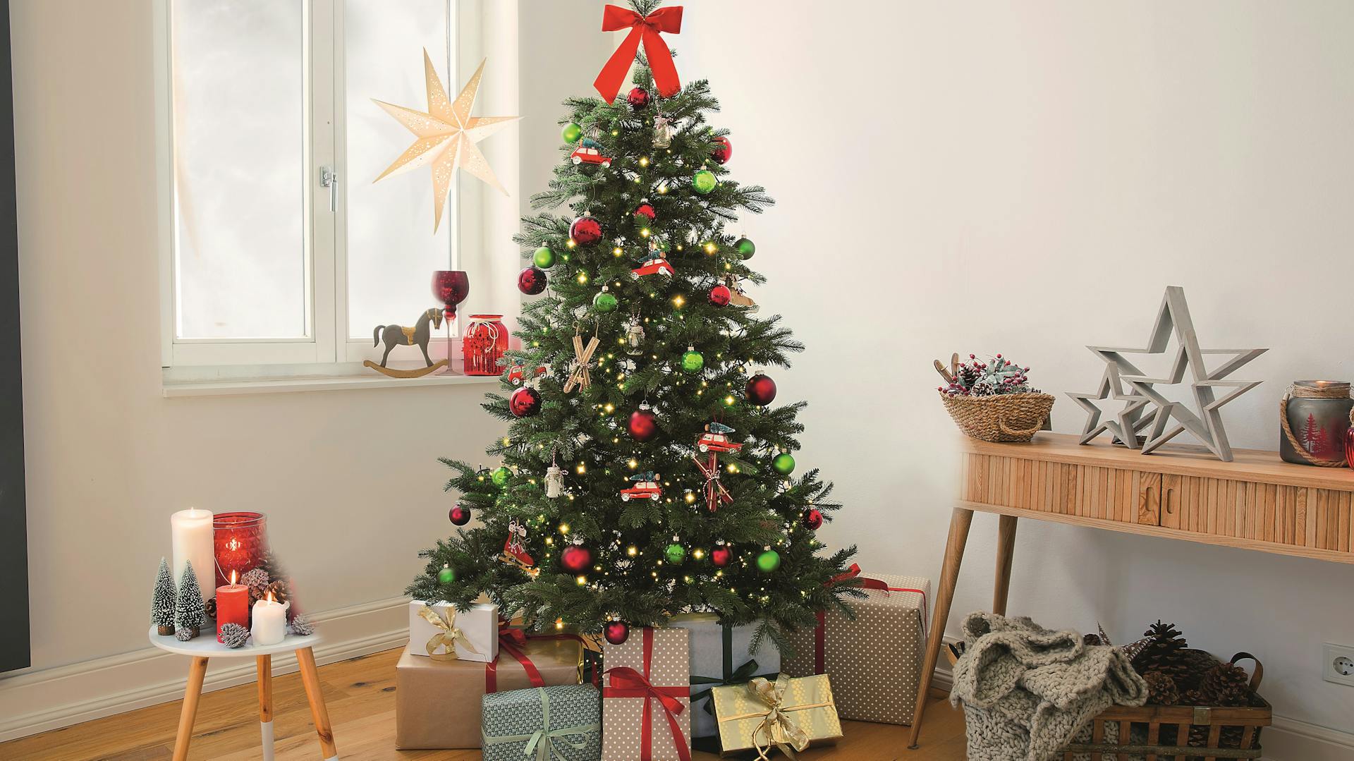Klassisch geschmückter Weihnachtsbaum mit roten und grünen Kugeln und Geschenken unter dem Baum