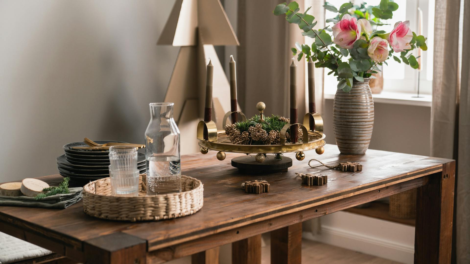 Selbstgemachte Dekoration mit Kerzen neben einem gold-geschmückten Weihnachtsbaum.