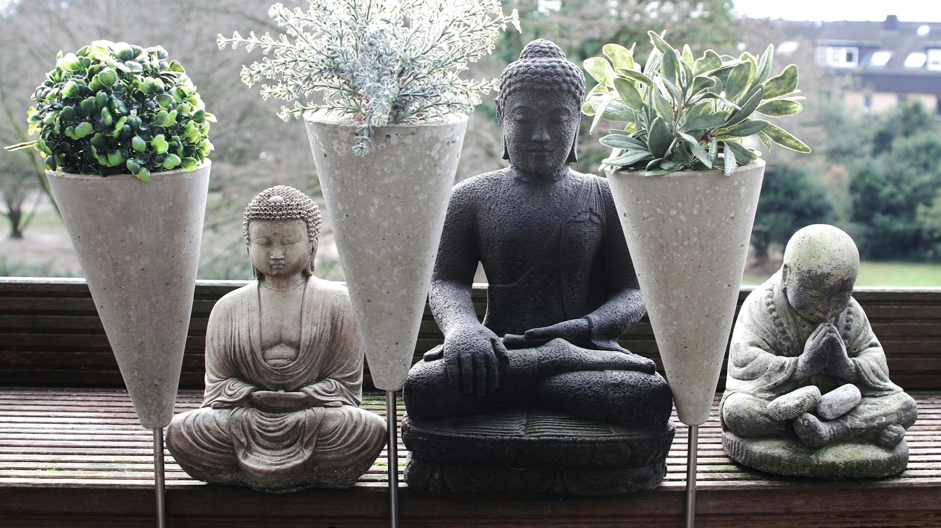 Buddha-Skulpturen und kegelförmige Blumentöpfe aus Bastelbeton an Fensterbank