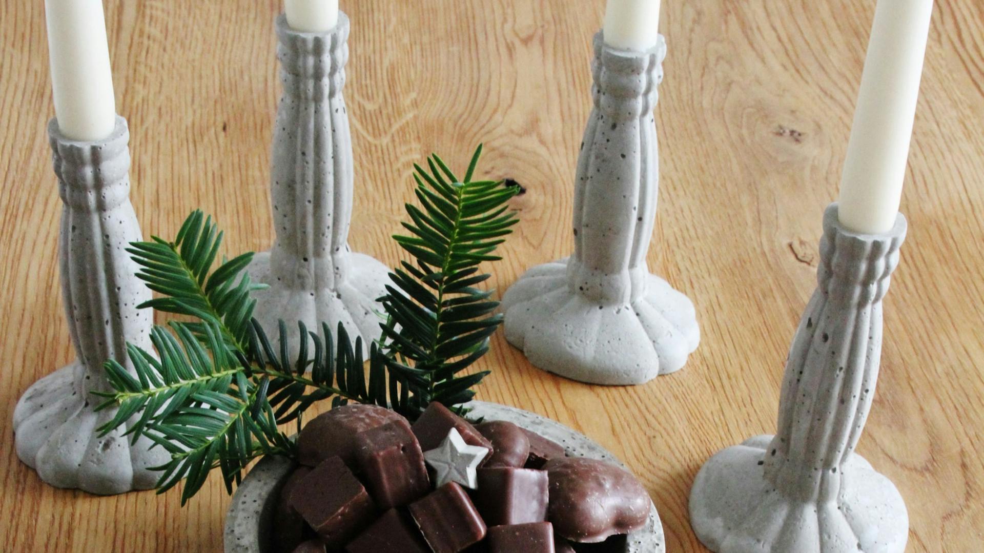 Kerzenhalter und Schale mit Weihnachtssüßigkeiten an Dekosternen aus Bastelbeton