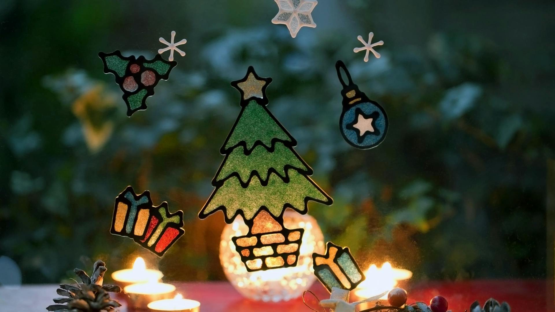 Weihnachtsbaum, Geschenke und Weihnachtsmotive, die mit Fensterfarbe auf ein Fenster gemalt wurden..