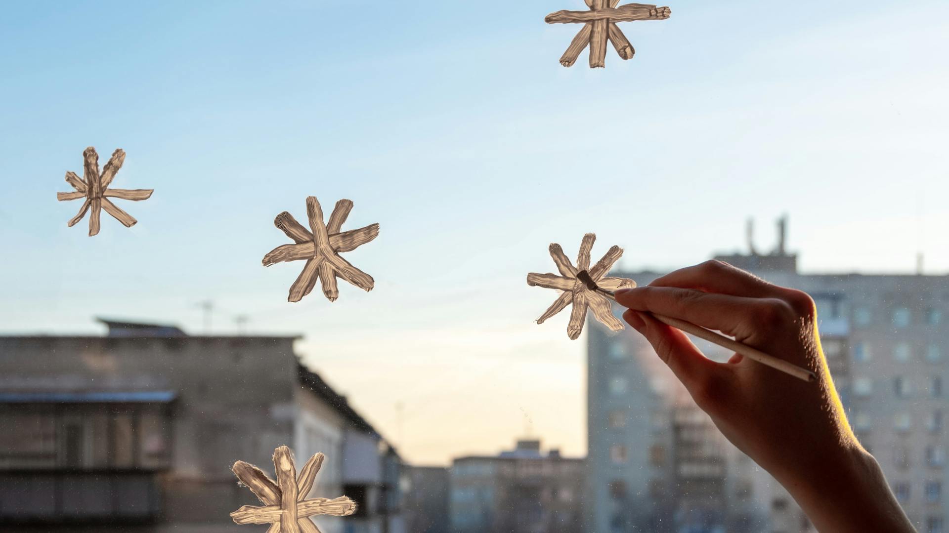 Jemand malt Sterne mit Fensterfarbe an eine Scheibe.