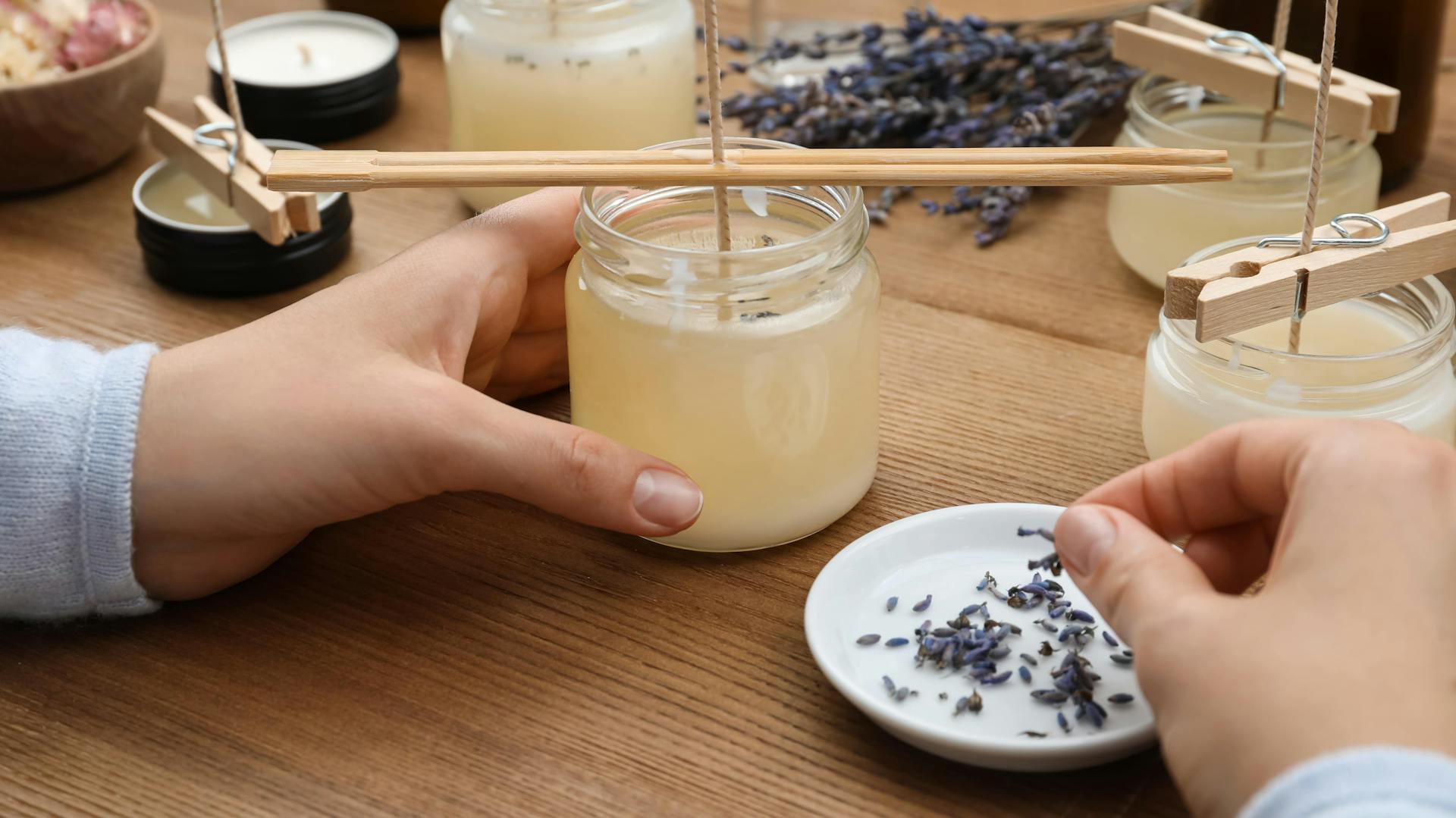 Eine Person hält eine selbst gemachte Kerze in der Hand, während sie sie dekoriert.