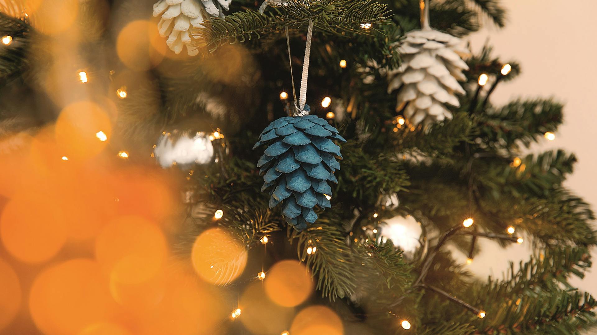 DIY-Baumschmuck: Ein bemalter Tannenzapfen schmückt den Weihnachtsbaum als natürliche Deko