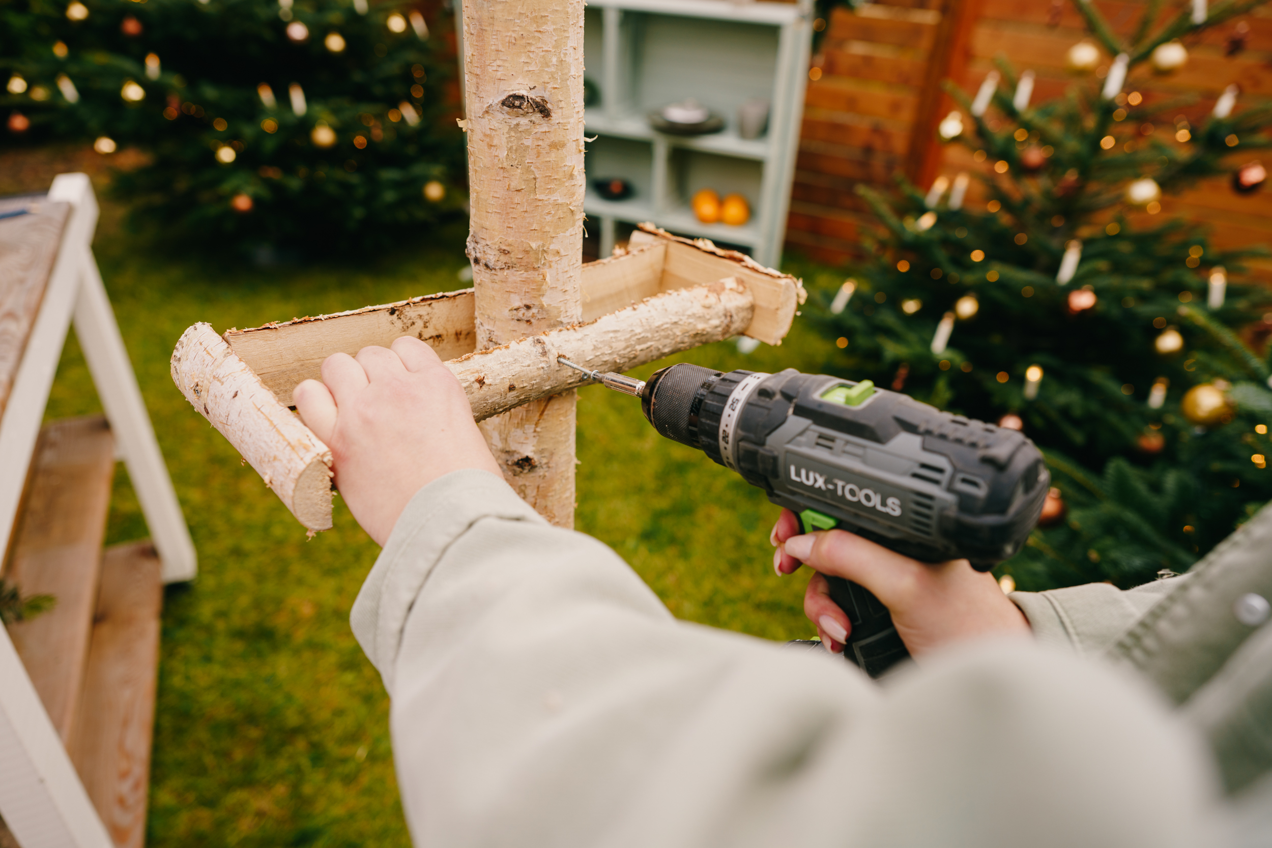 Pracovníčka upevňuje konštrukciu na kmeň adventného venca.