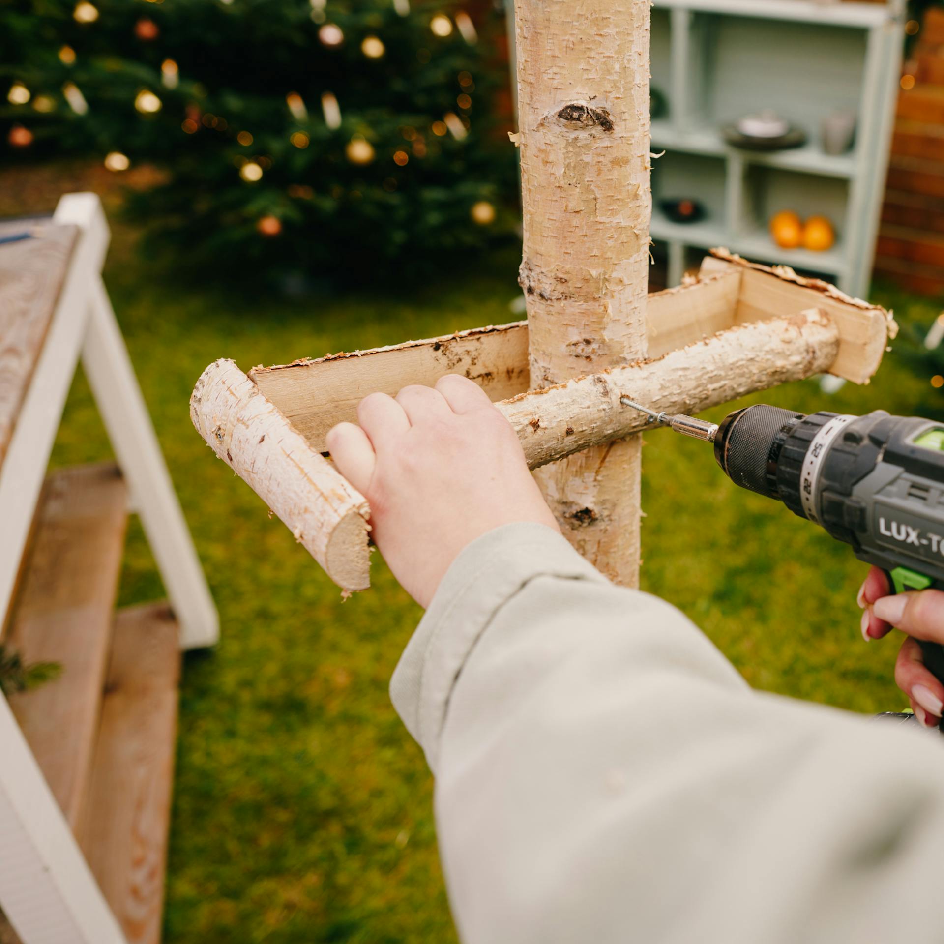 Pracovníčka upevňuje konštrukciu na kmeň adventného venca.
