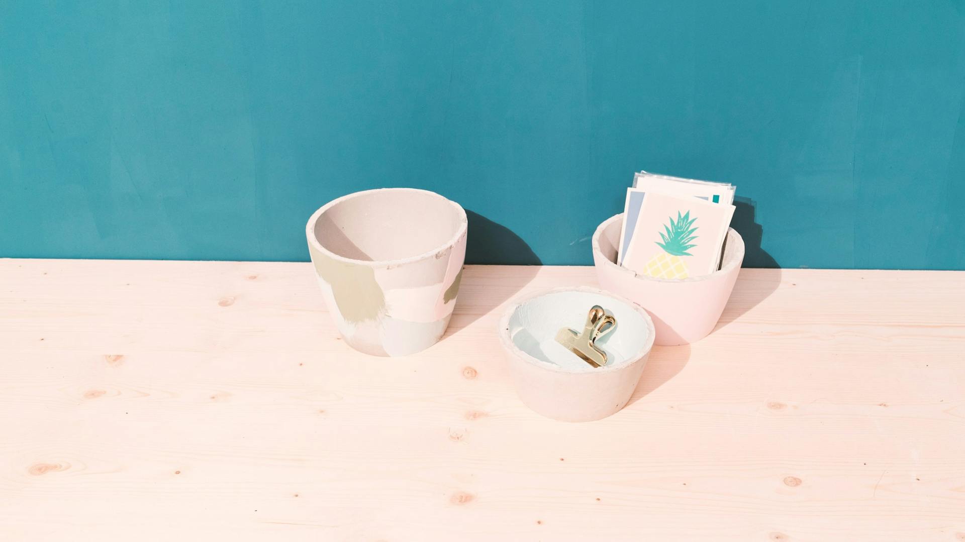 Schalen aus Beton auf Holzbrett vor türkiser Wand