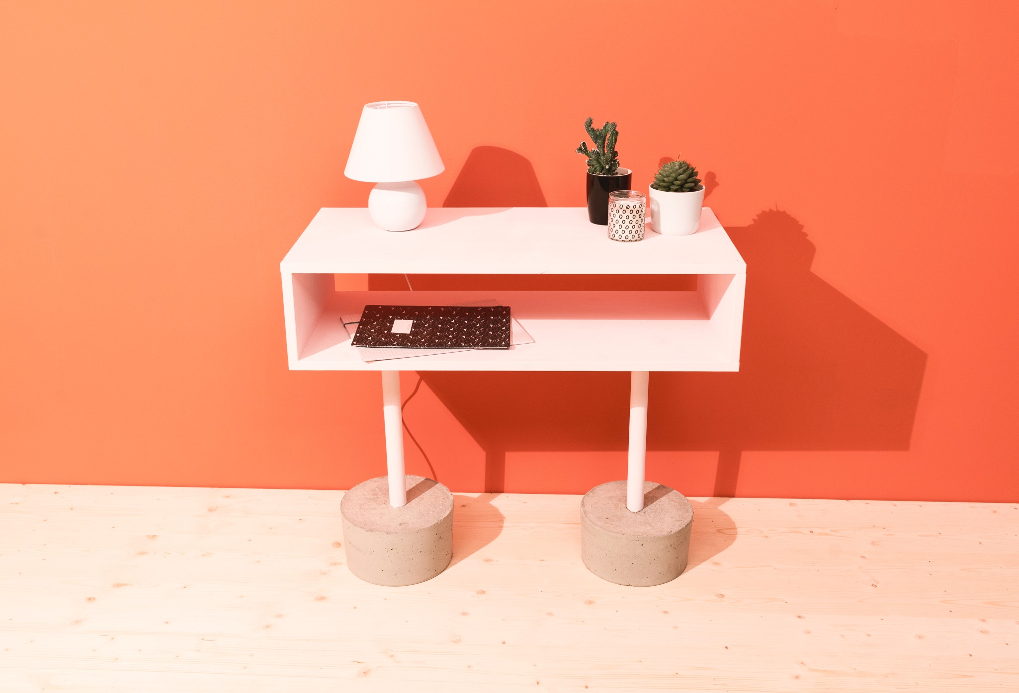 Sideboard mit zwei Füßen aus Beton auf Holzboden vor oranger Wand