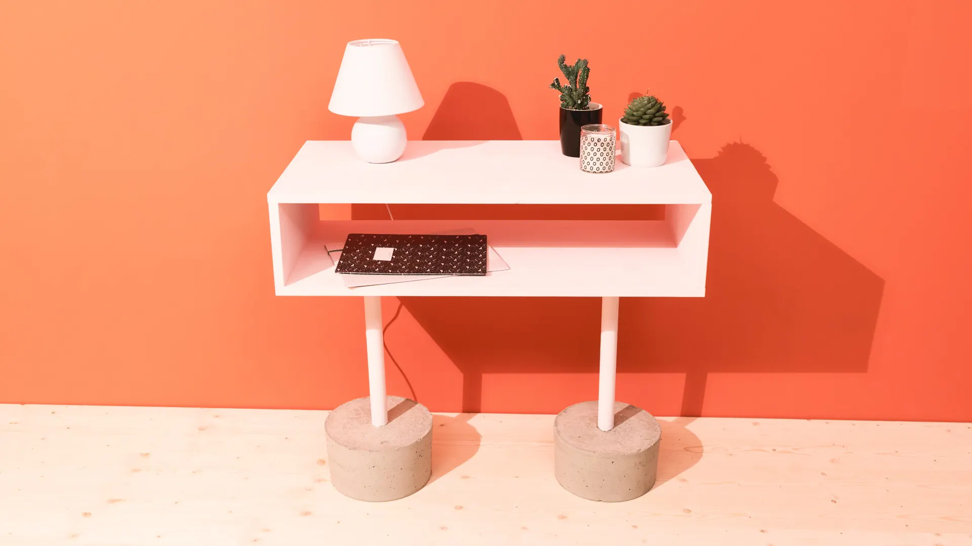 Sideboard mit zwei Füßen aus Beton auf Holzboden vor oranger Wand