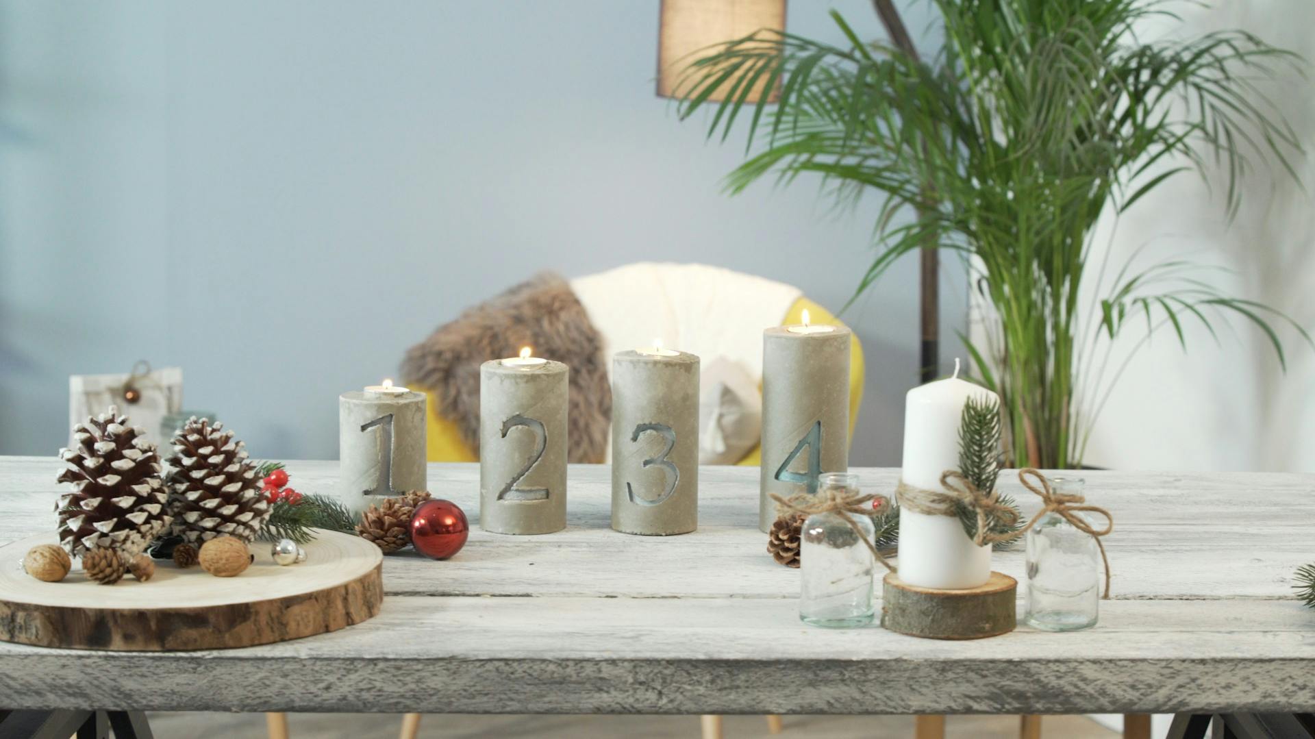 Vier Adventskerzenständer aus Beton auf einem dekorierten Tisch