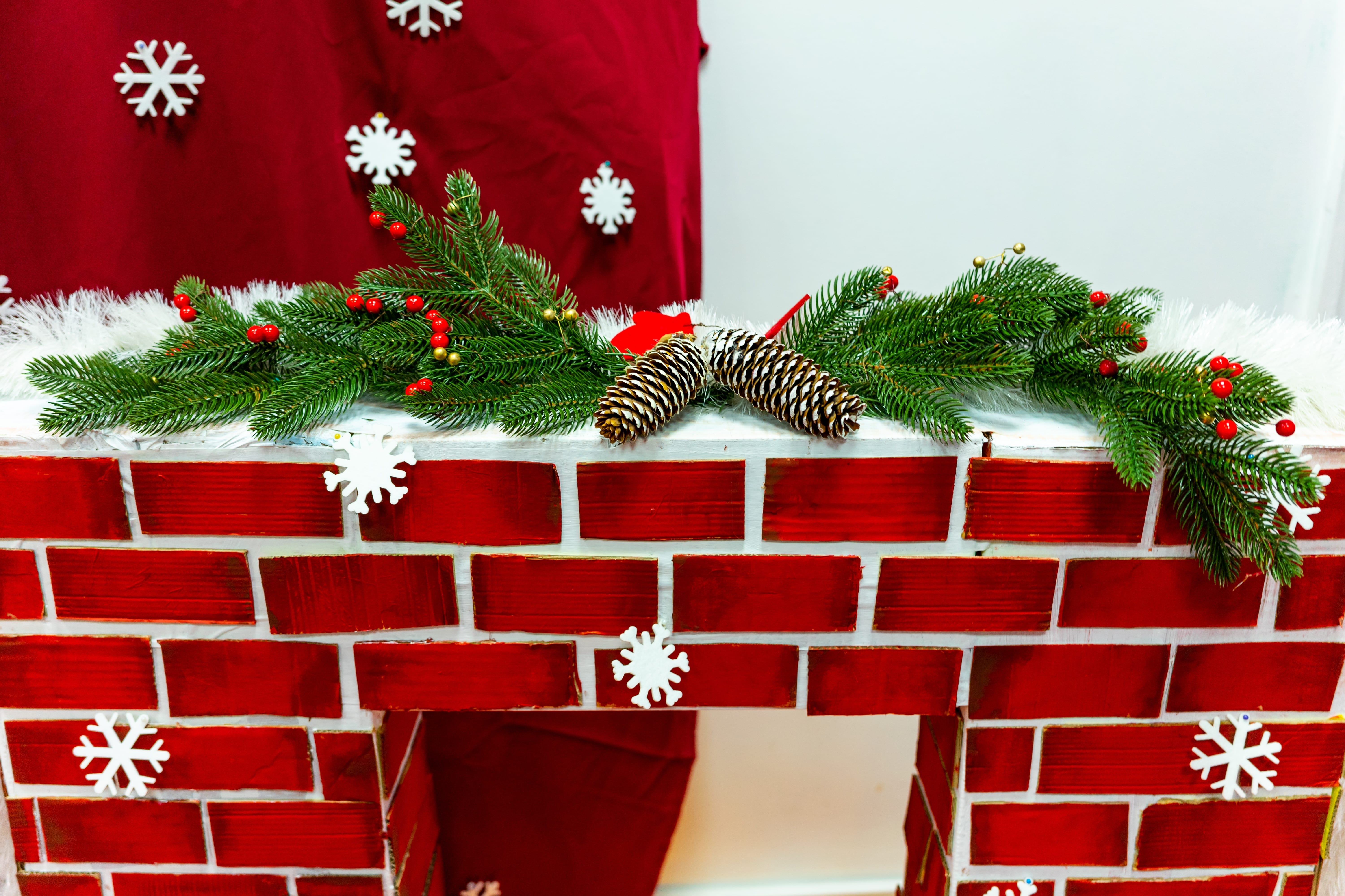 Dekokamin in roter Ziegeloptik mit weihnachtlicher Dekogirlande