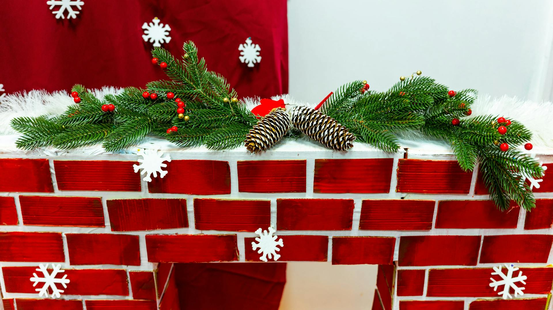 Dekokamin in roter Ziegeloptik mit weihnachtlicher Dekogirlande