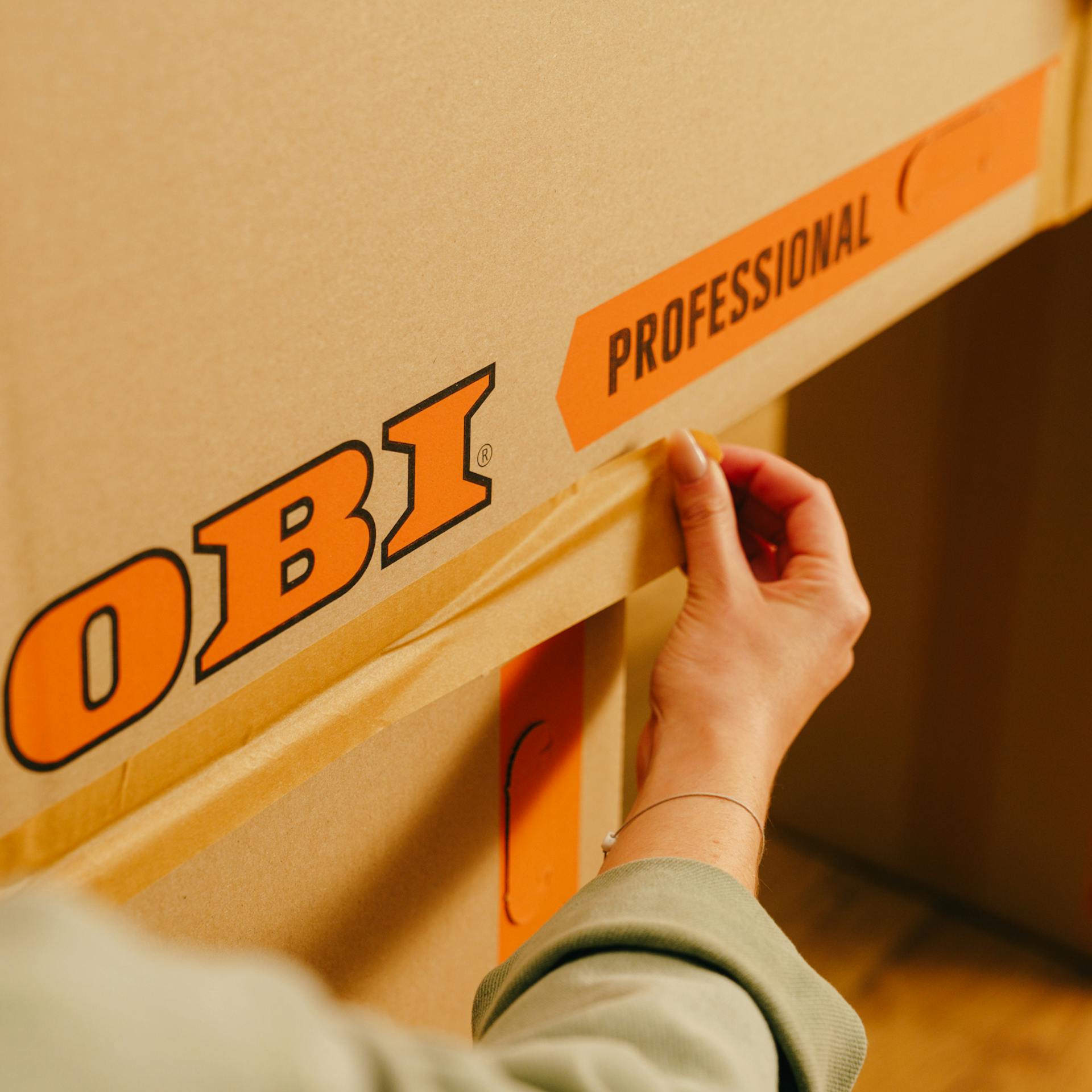 Handwerkerin verklebt die Kartons miteinander.