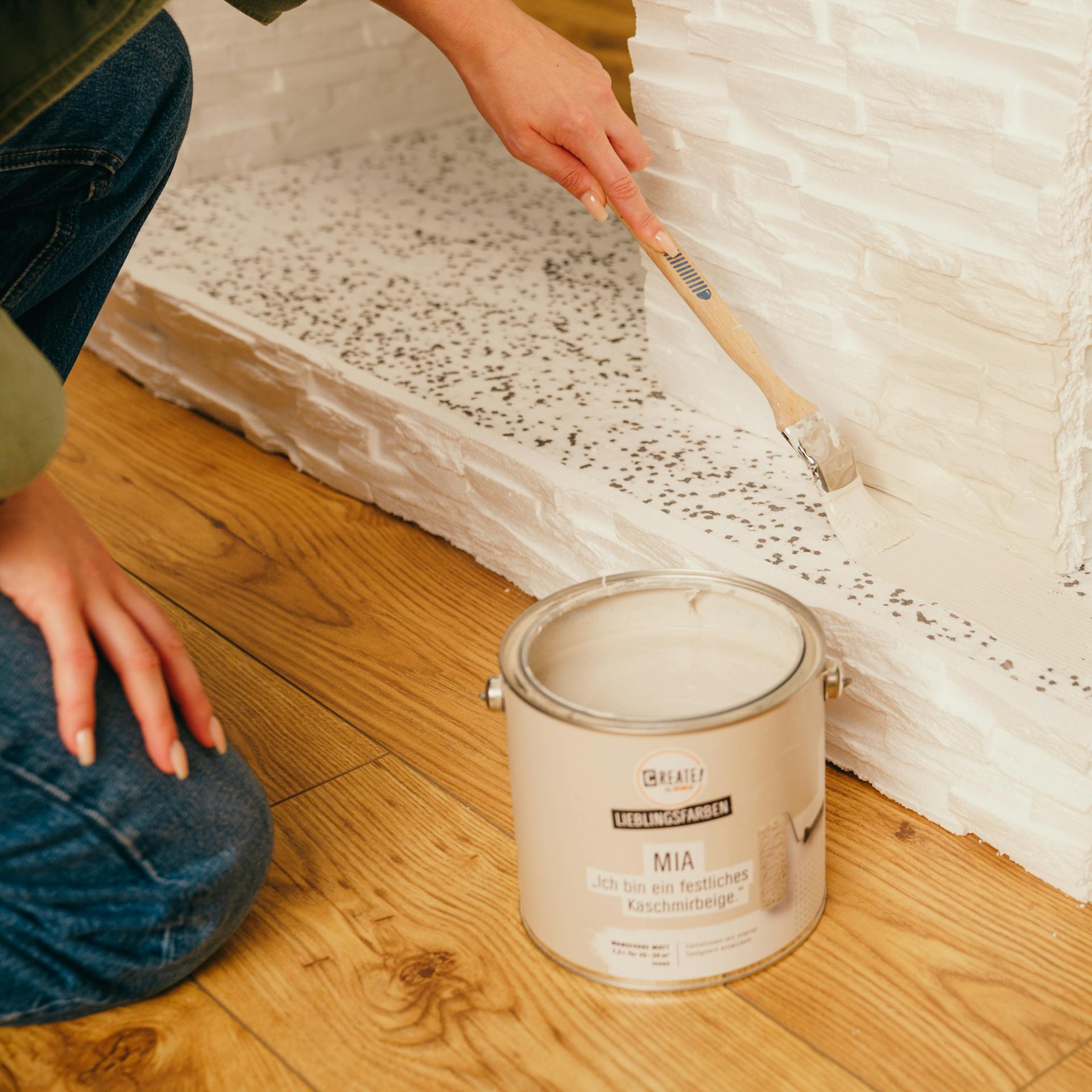 Handwerkerin streicht den Kamin in weiß.