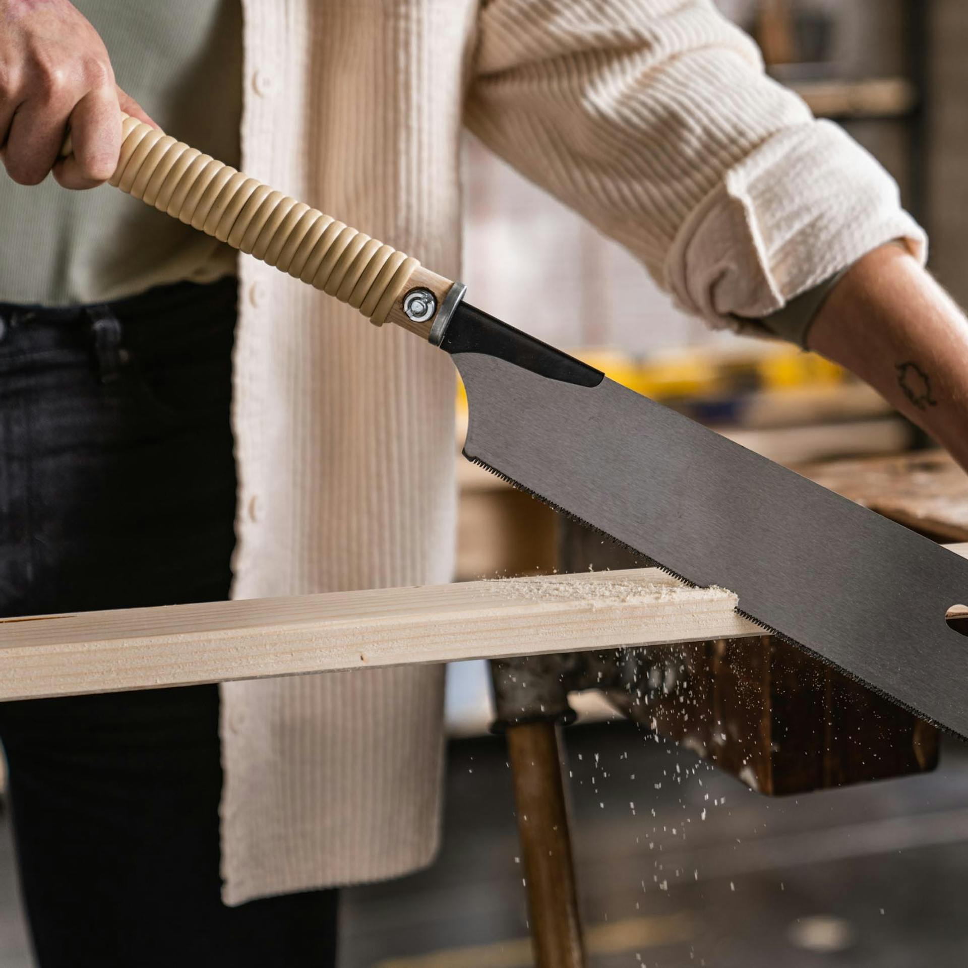 Rahmenholz wird von Handwerkerin mit einer Japansäge zugeschnitten.