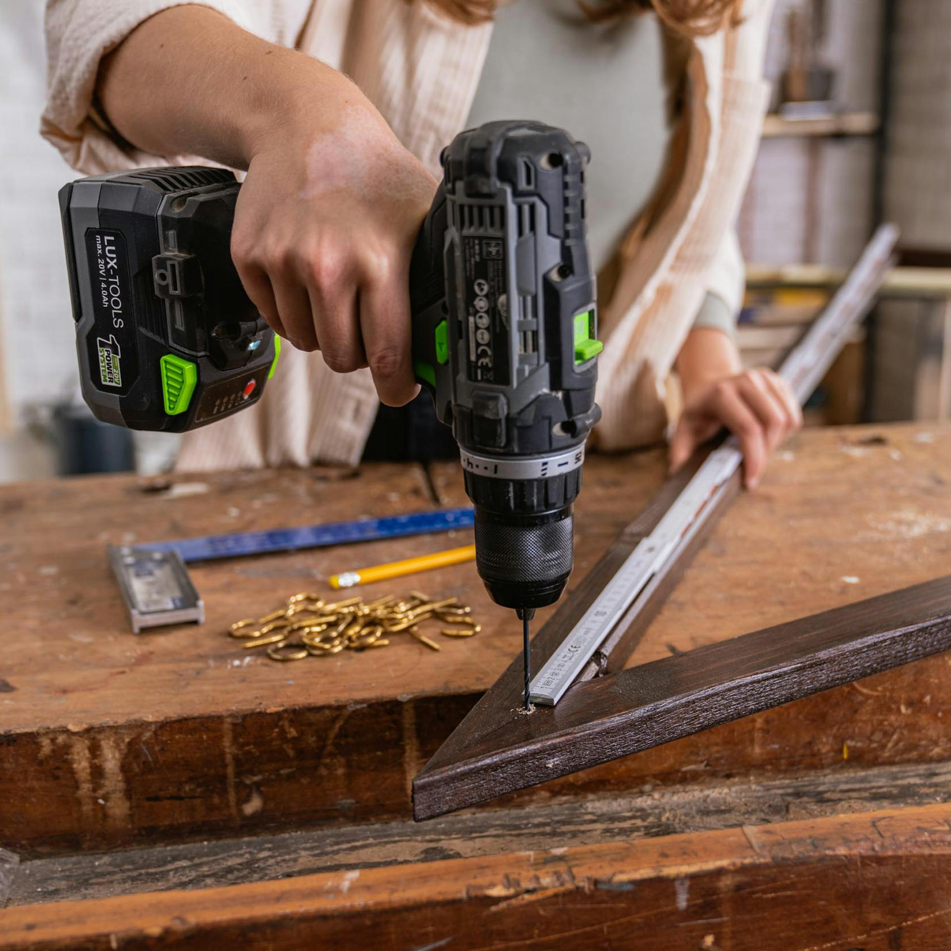 Handwerkerin bohrt Löcher in Rahmenholz vor.